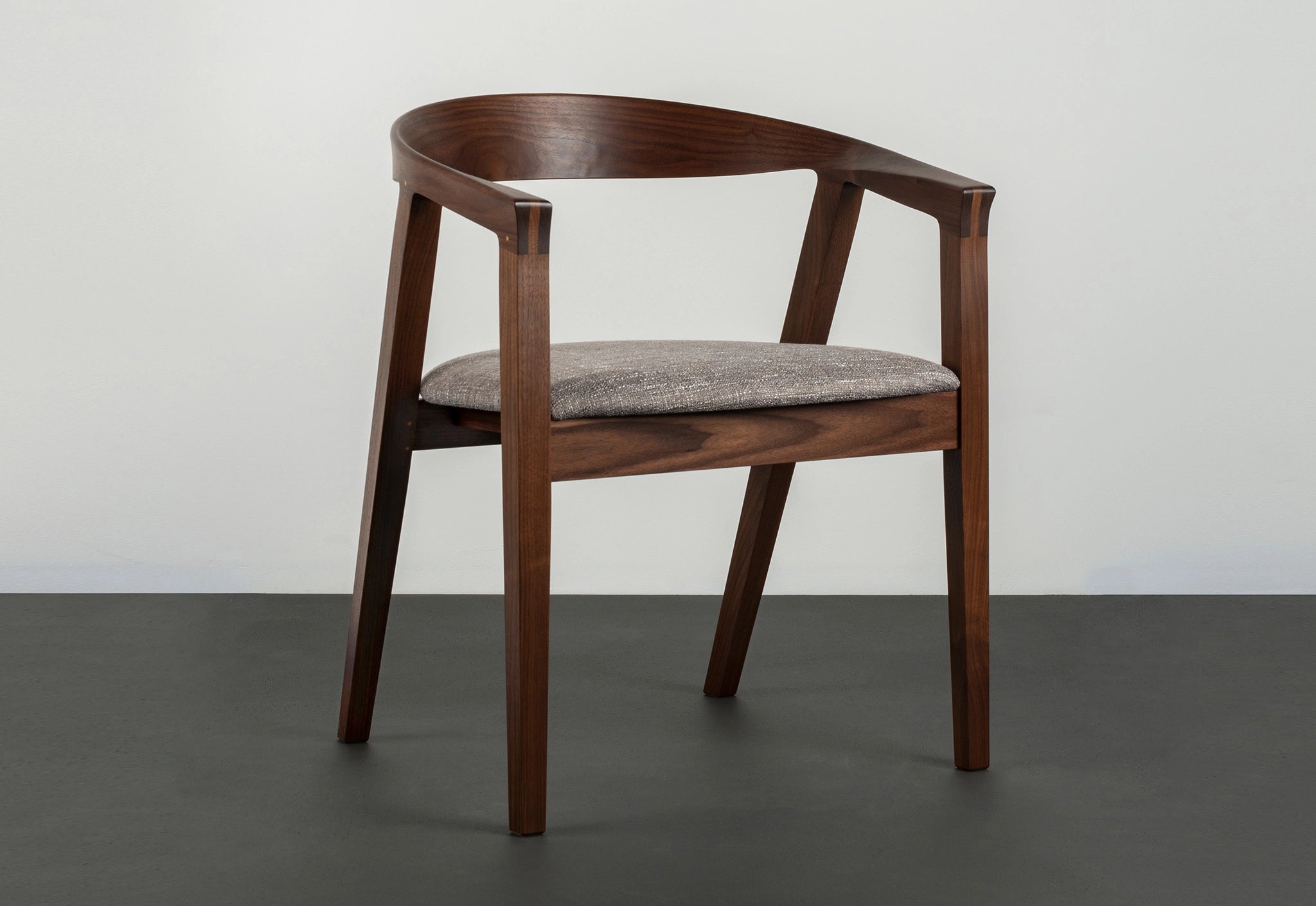 Wooden chair with a gray cushion on a dark surface and light gray background
