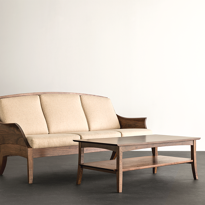 Wing Sofa in walnut with white upholstery and wing coffee table in walnut. Studio setting.
