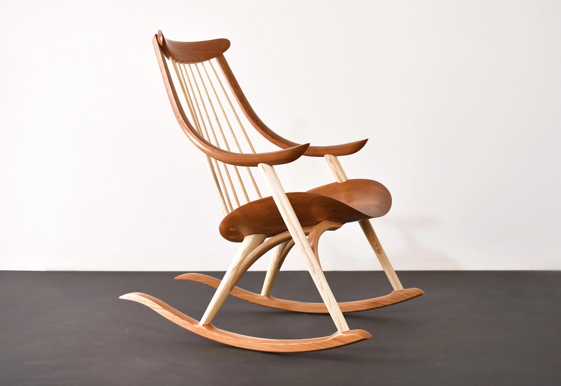 Wooden rocking chair on a dark surface with a light background