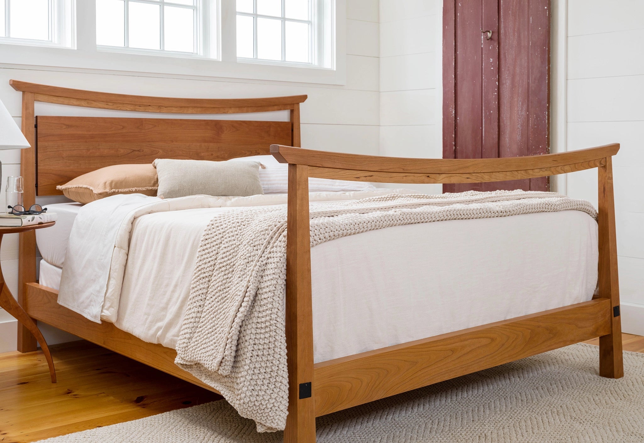 Cherry bungalow style bed in a white room with a red door.