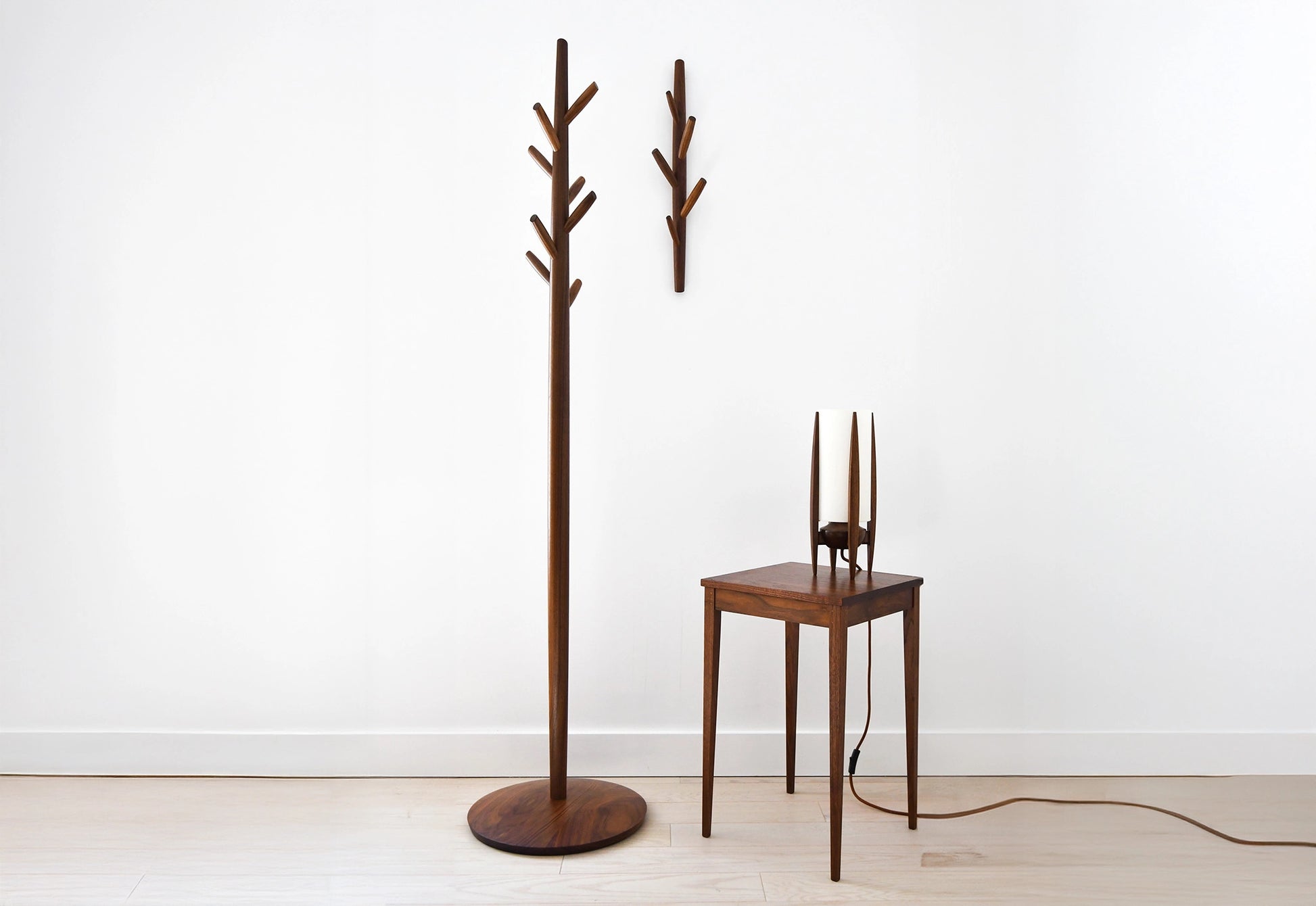 Wooden coat tree and side table against a white wall