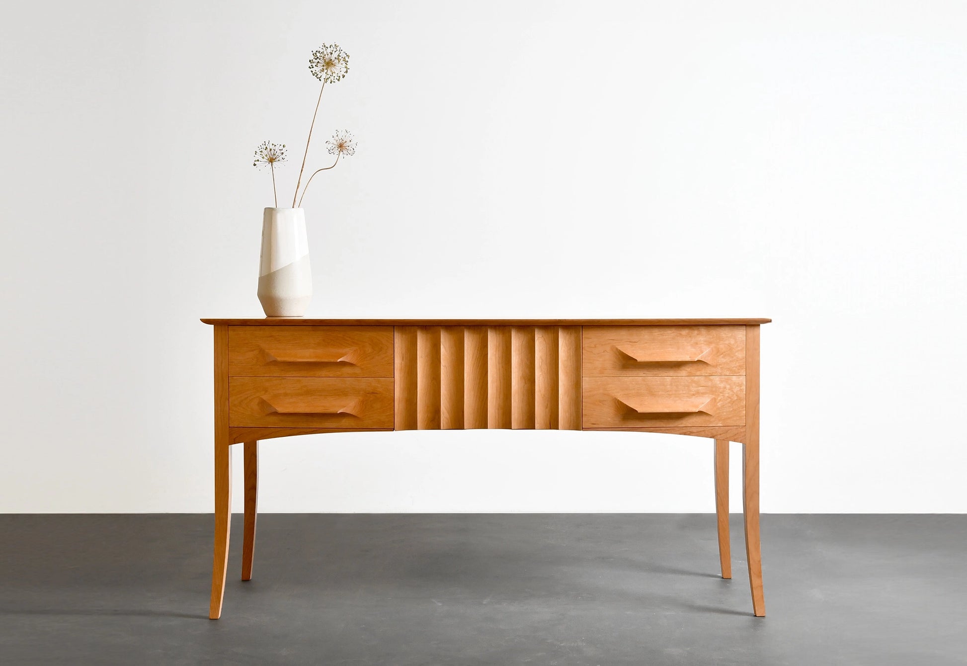 Wooden sideboard with a vase of flowers on a plain background