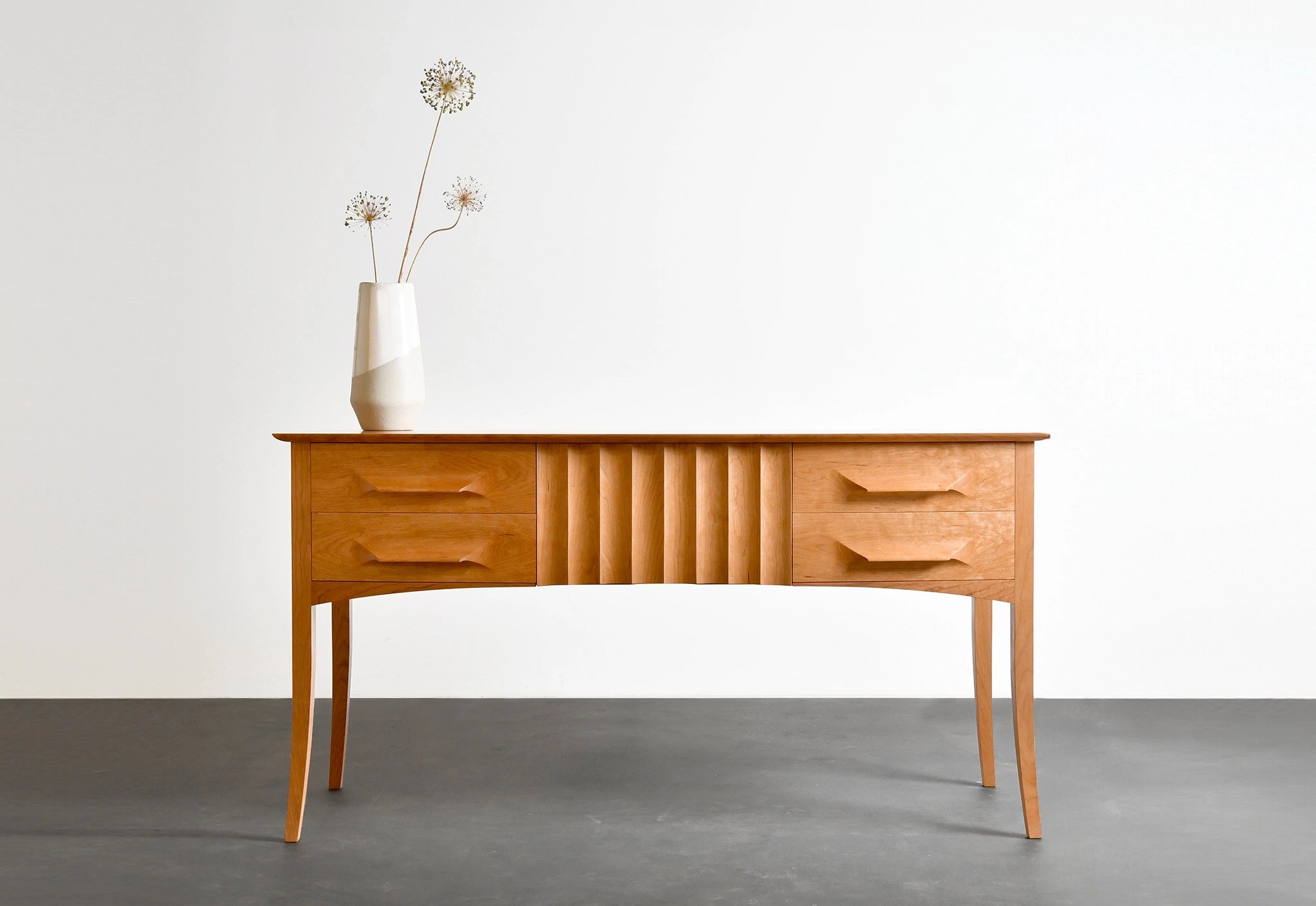 Wooden sideboard with a vase of flowers on a plain background