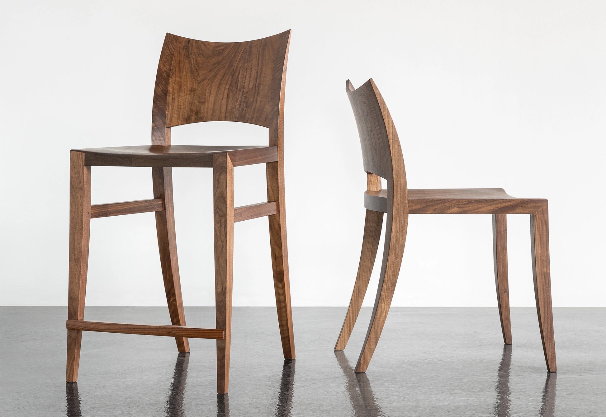 Two wooden chairs on a reflective surface with a white background