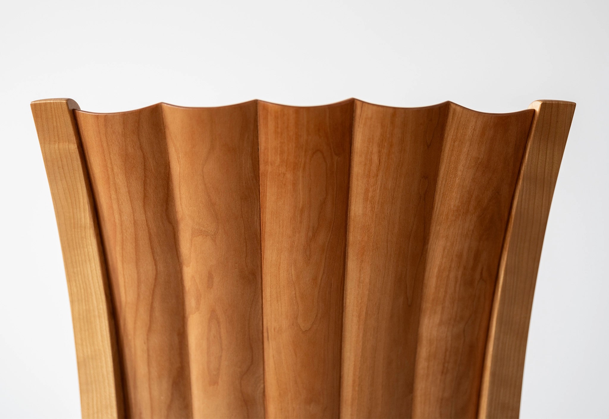 Wooden chair detail with wavy design on a white background