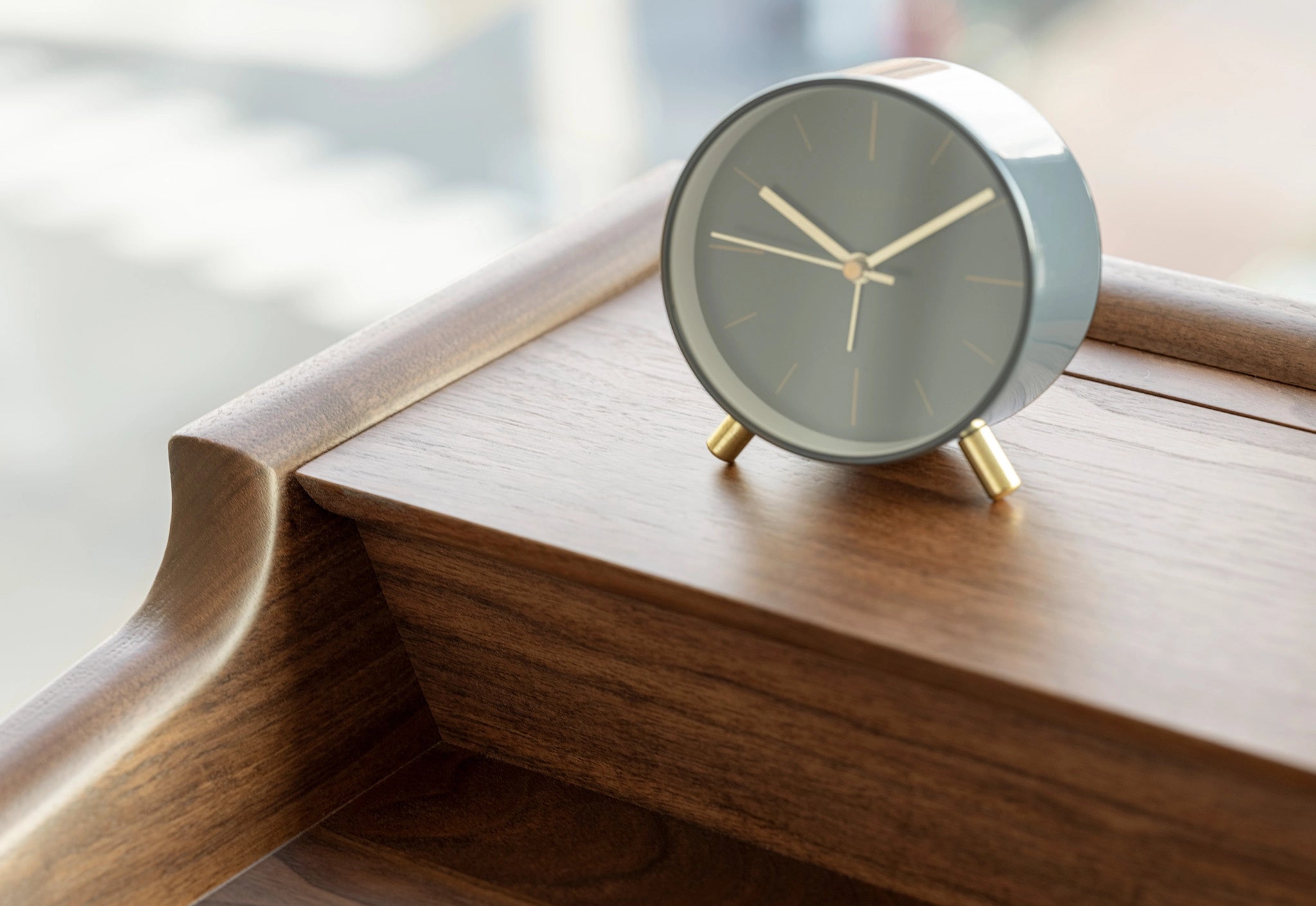 Small round clock with gold accents on a wooden surface