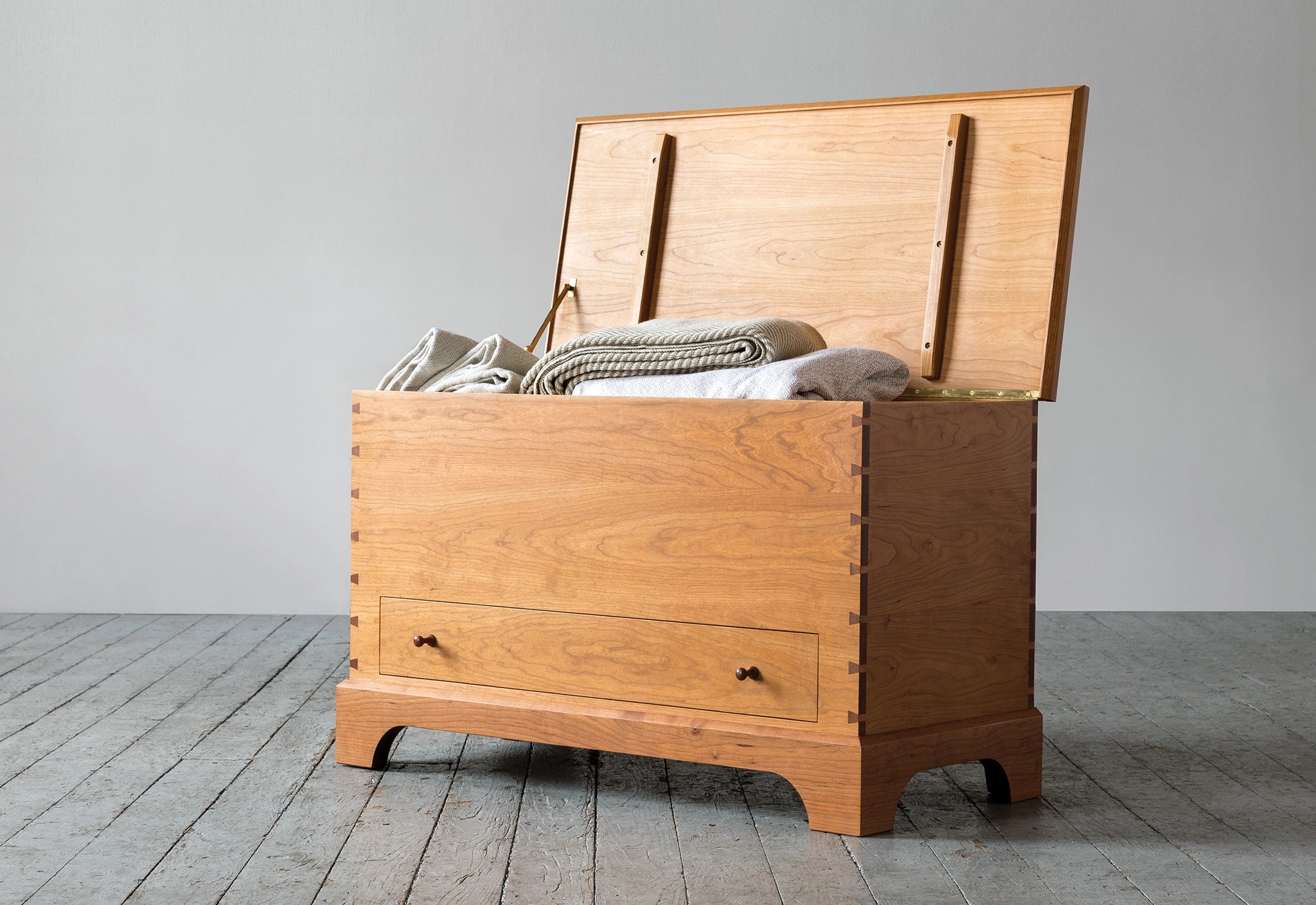 Wooden chest with clothes on a gray floor and wall background
