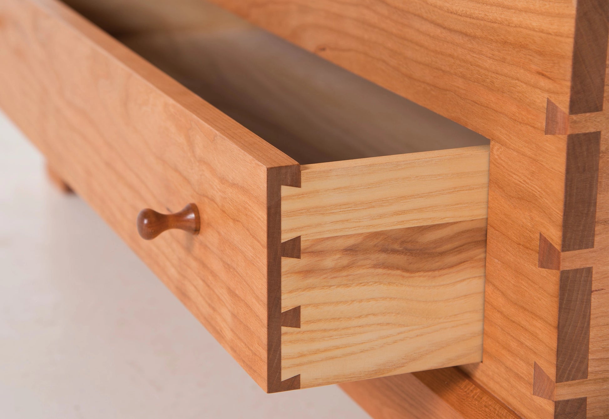 Close-up of a wooden drawer with dovetail joints on a light background