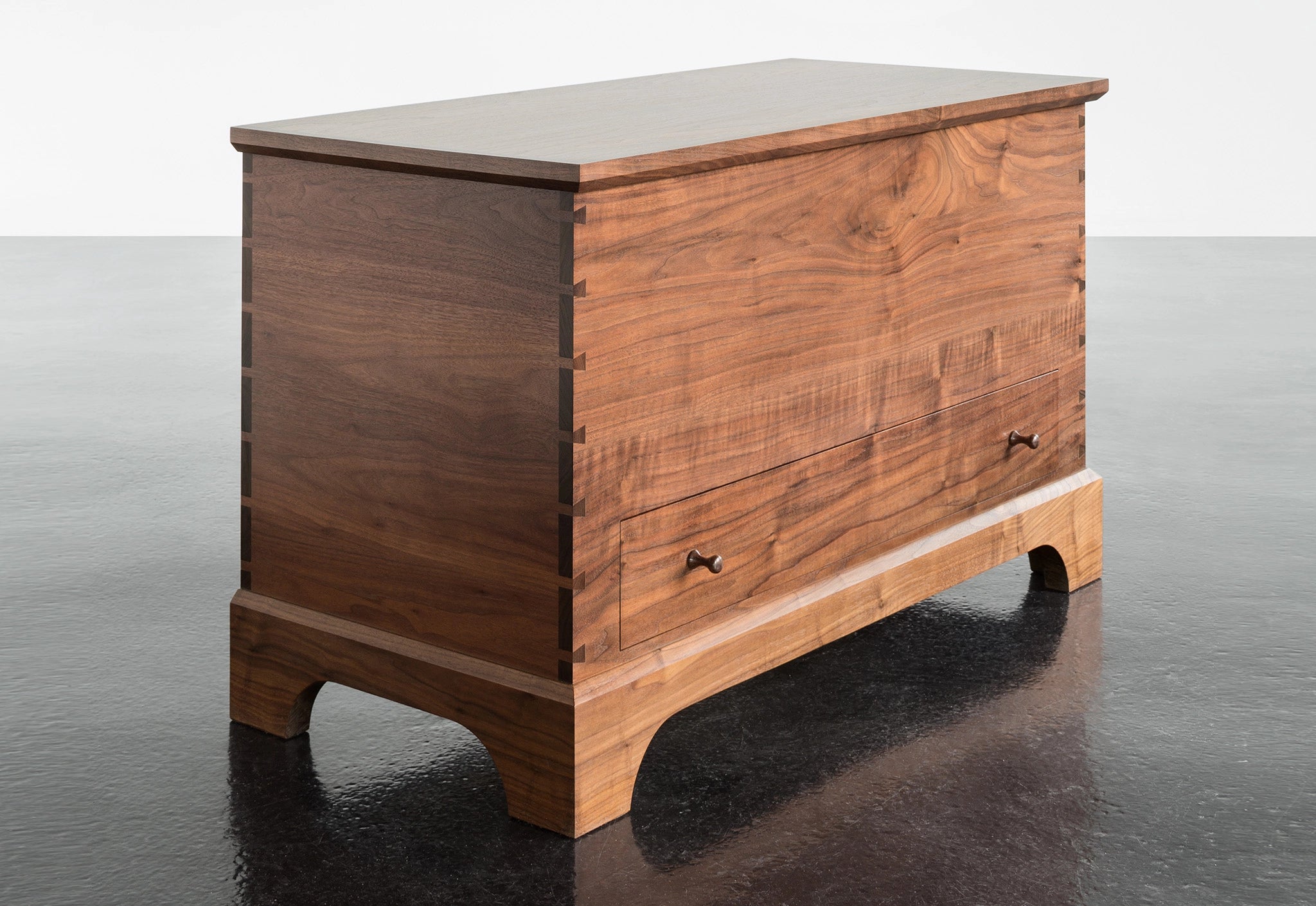 Wooden dresser with a white top on a reflective black surface