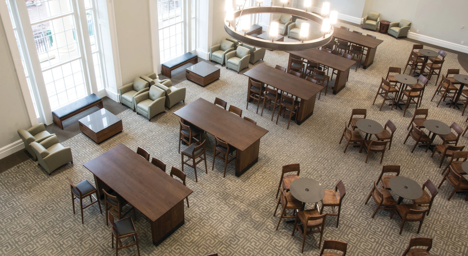 Large open room with tables and chairs arranged for dining or meeting, large windows allowing natural light.