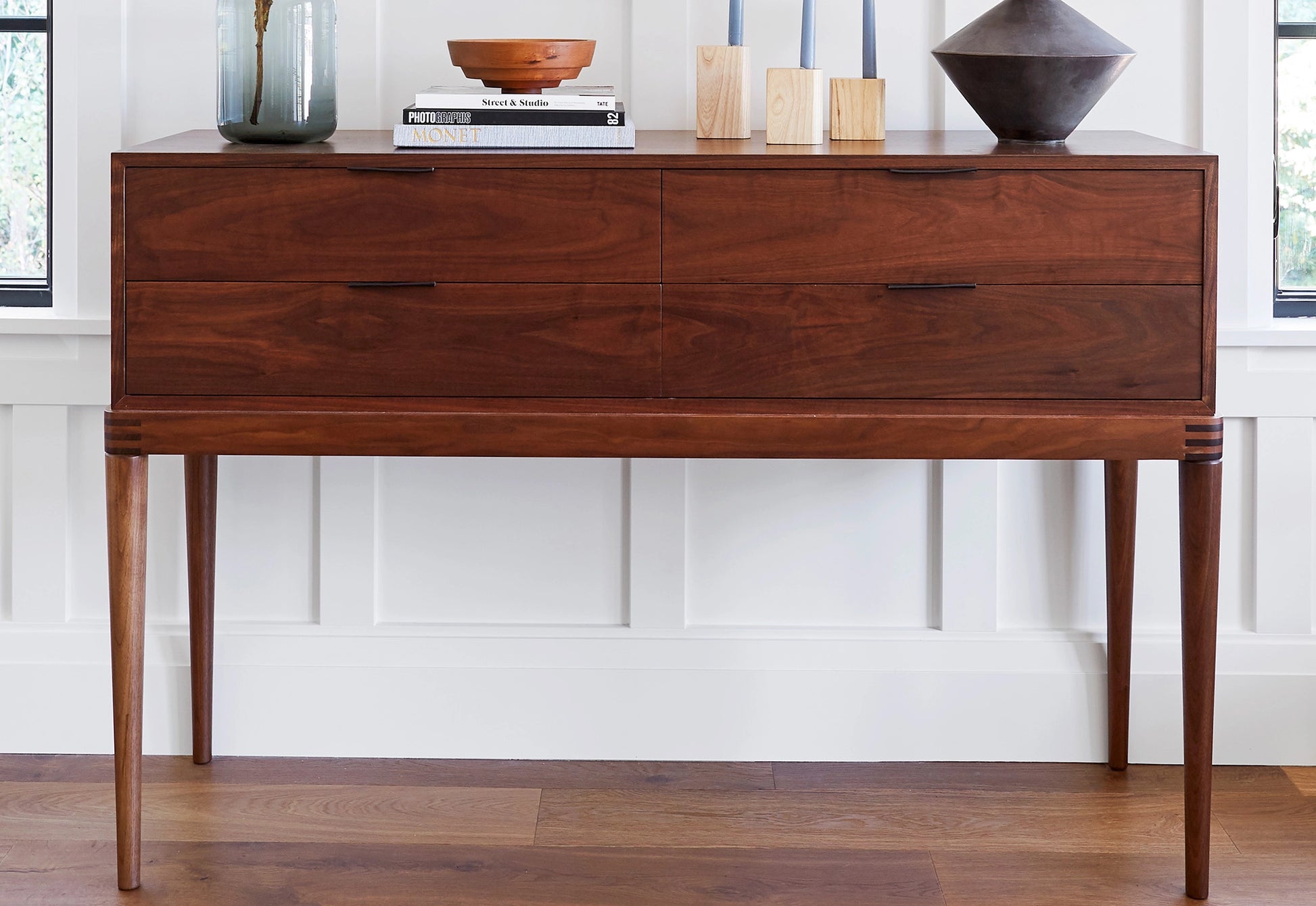 Wooden console table with decorative items against a white wall