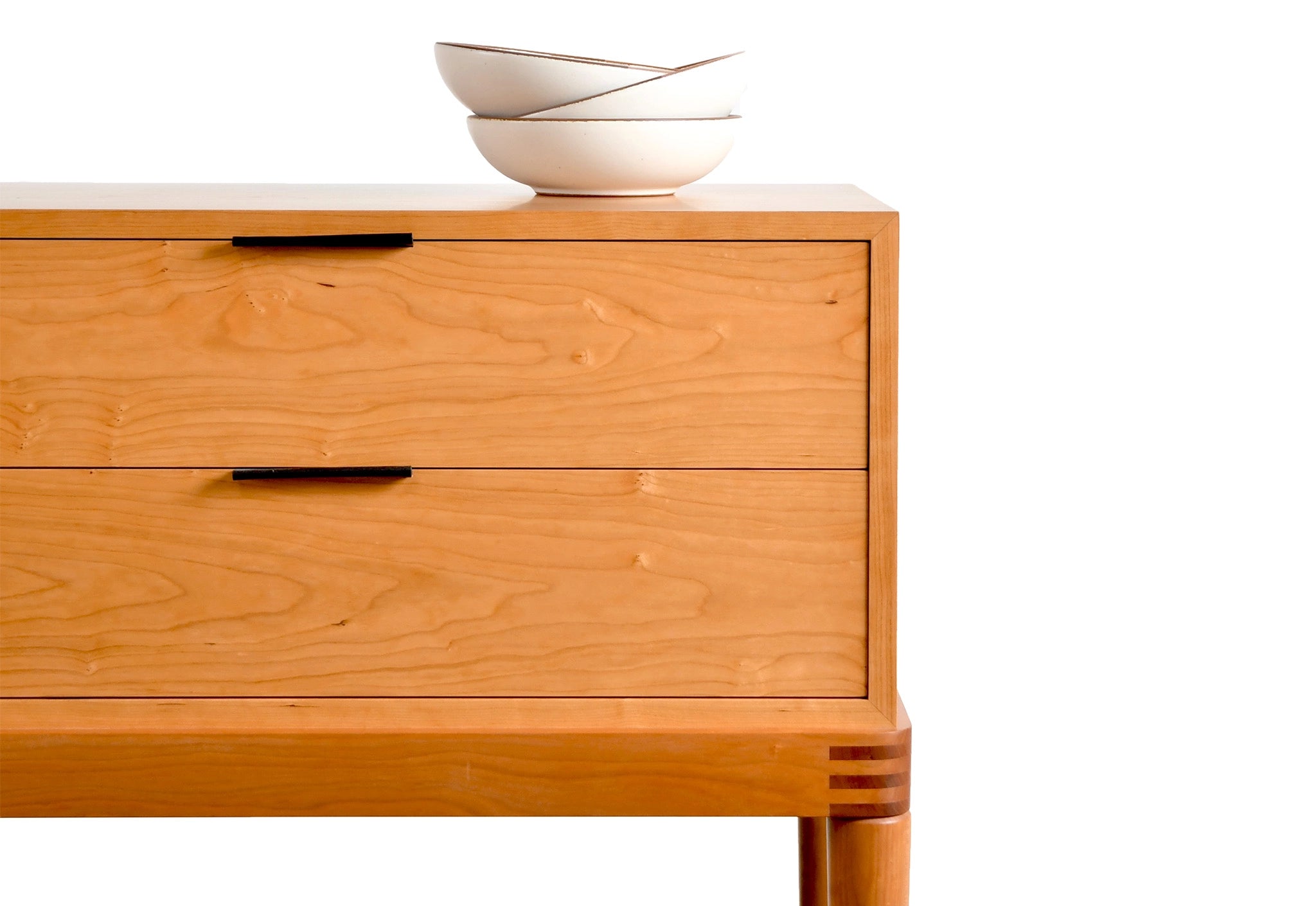 Wooden sideboard with two drawers and a white bowl on top against a white background