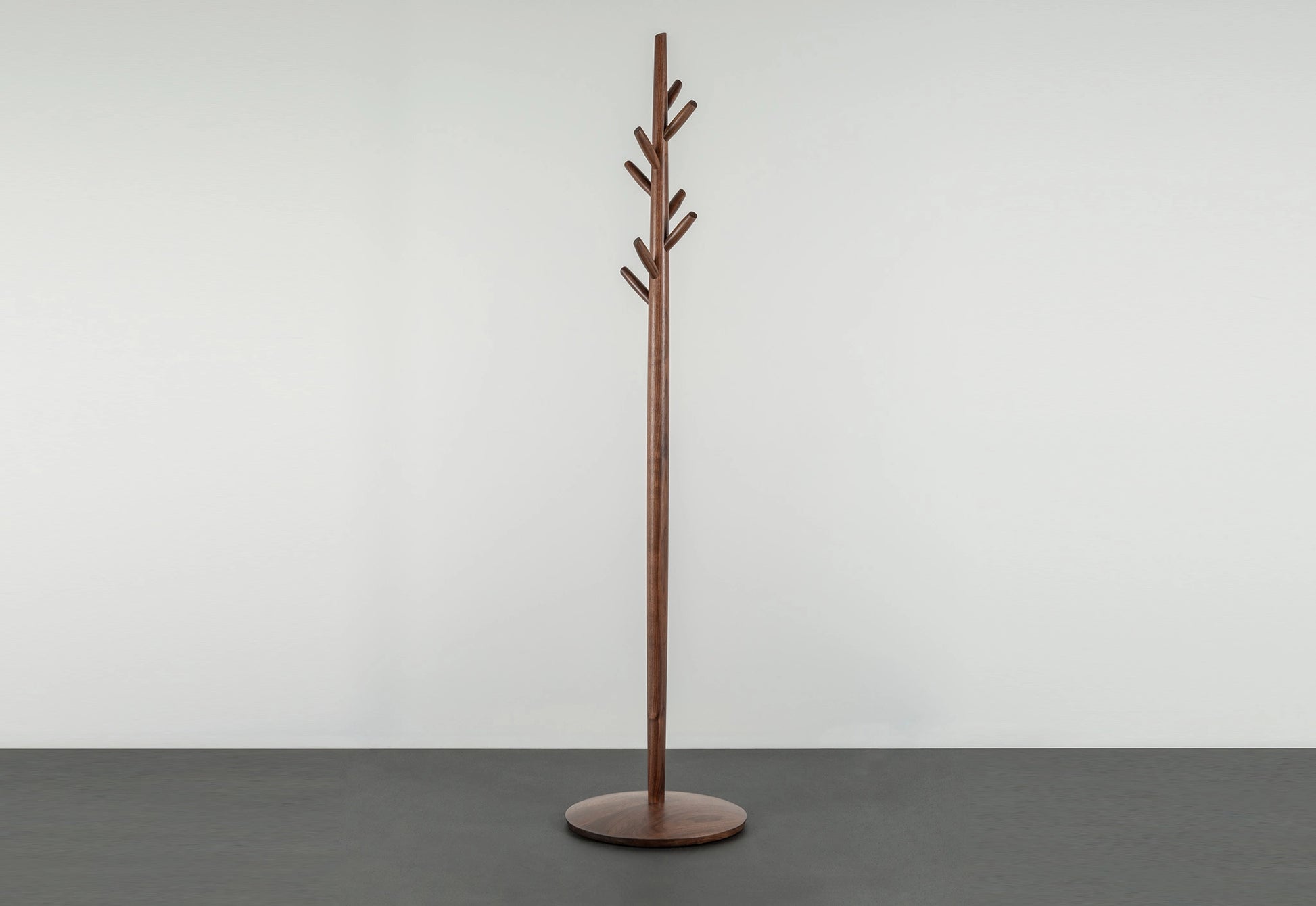 Wooden coat tree on a gray surface with a white background