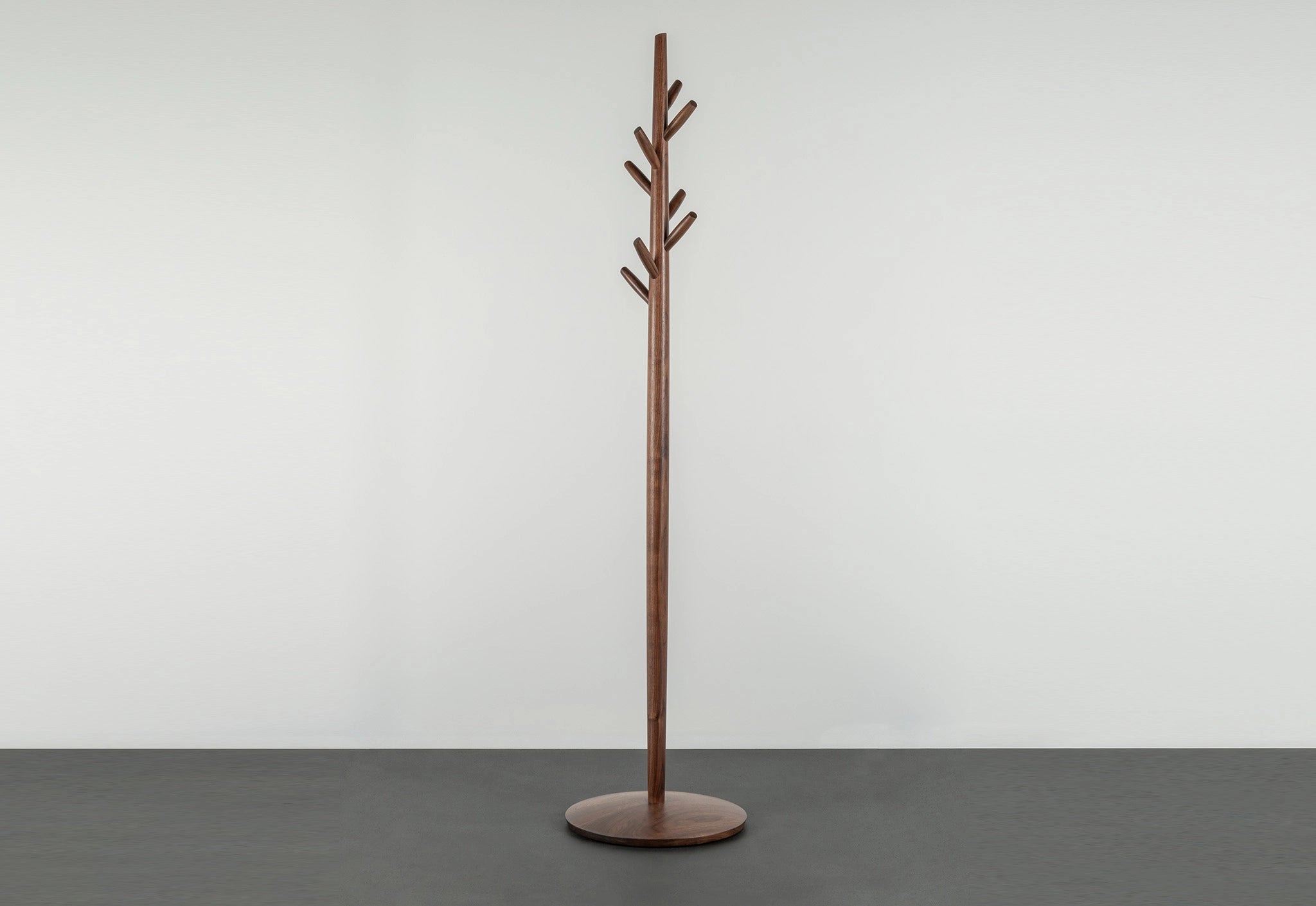 Wooden coat tree on a gray surface with a white background