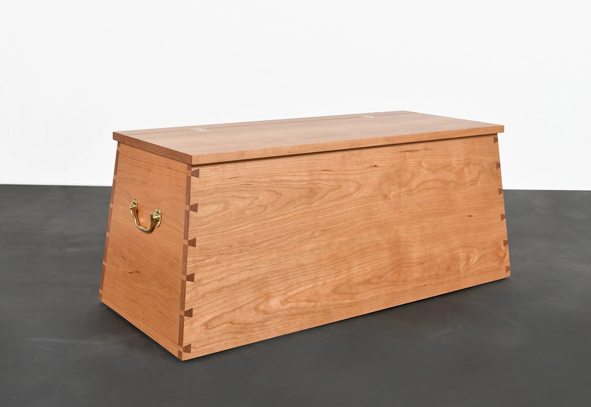 Wooden storage chest on a dark floor with a white background