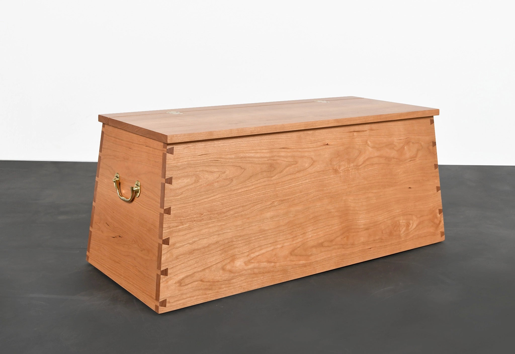 Wooden storage chest on a dark floor with a white background