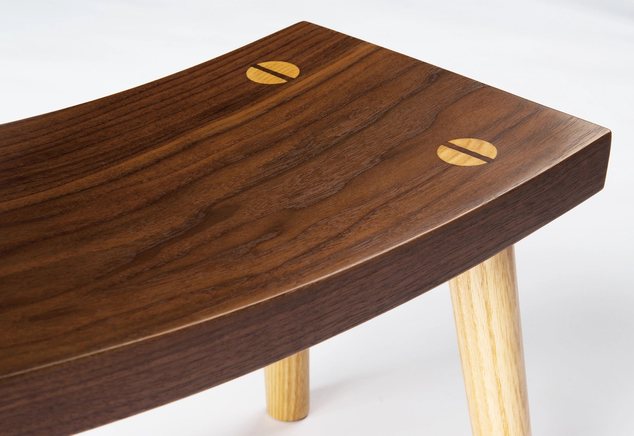 Wooden footstool with a dark brown top and light wood legs on a white background