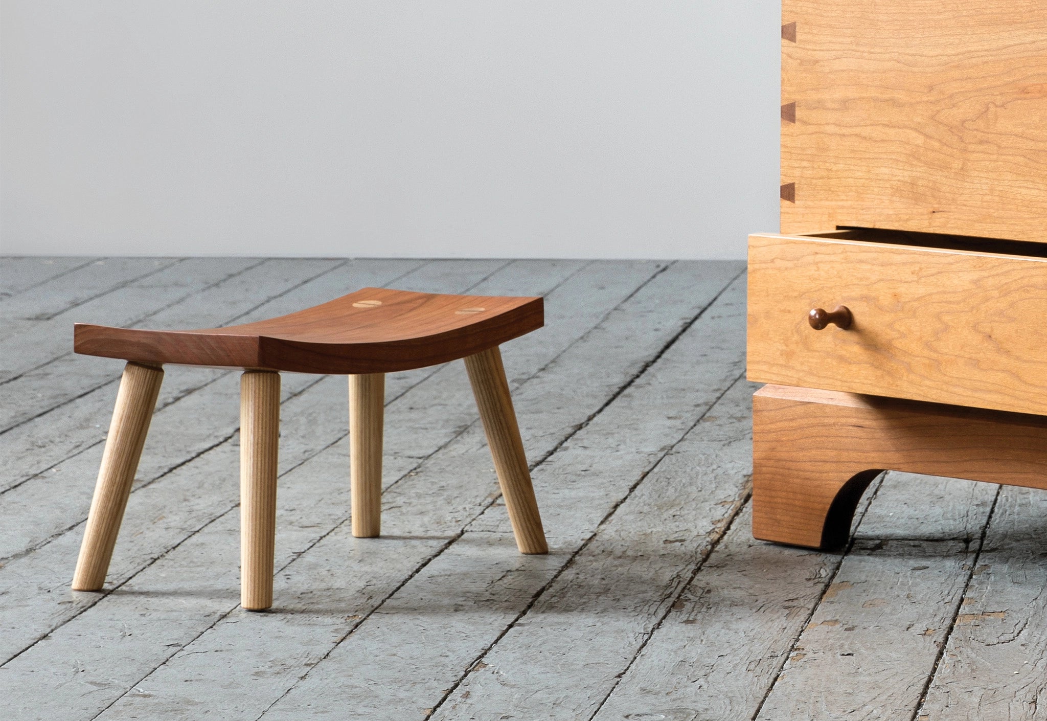 Wooden stool and chest on a wooden floor with a gray wall background