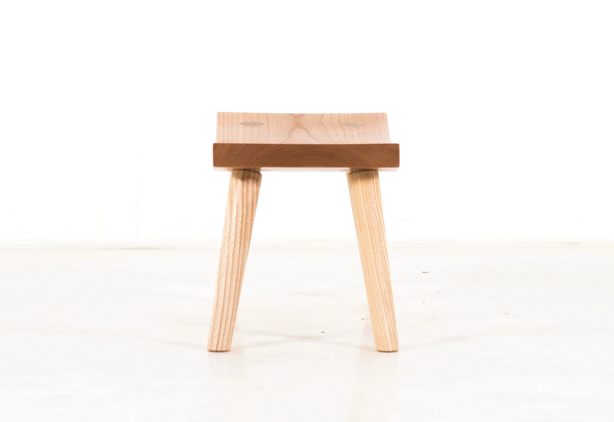 Wooden stool with a light finish on a white background