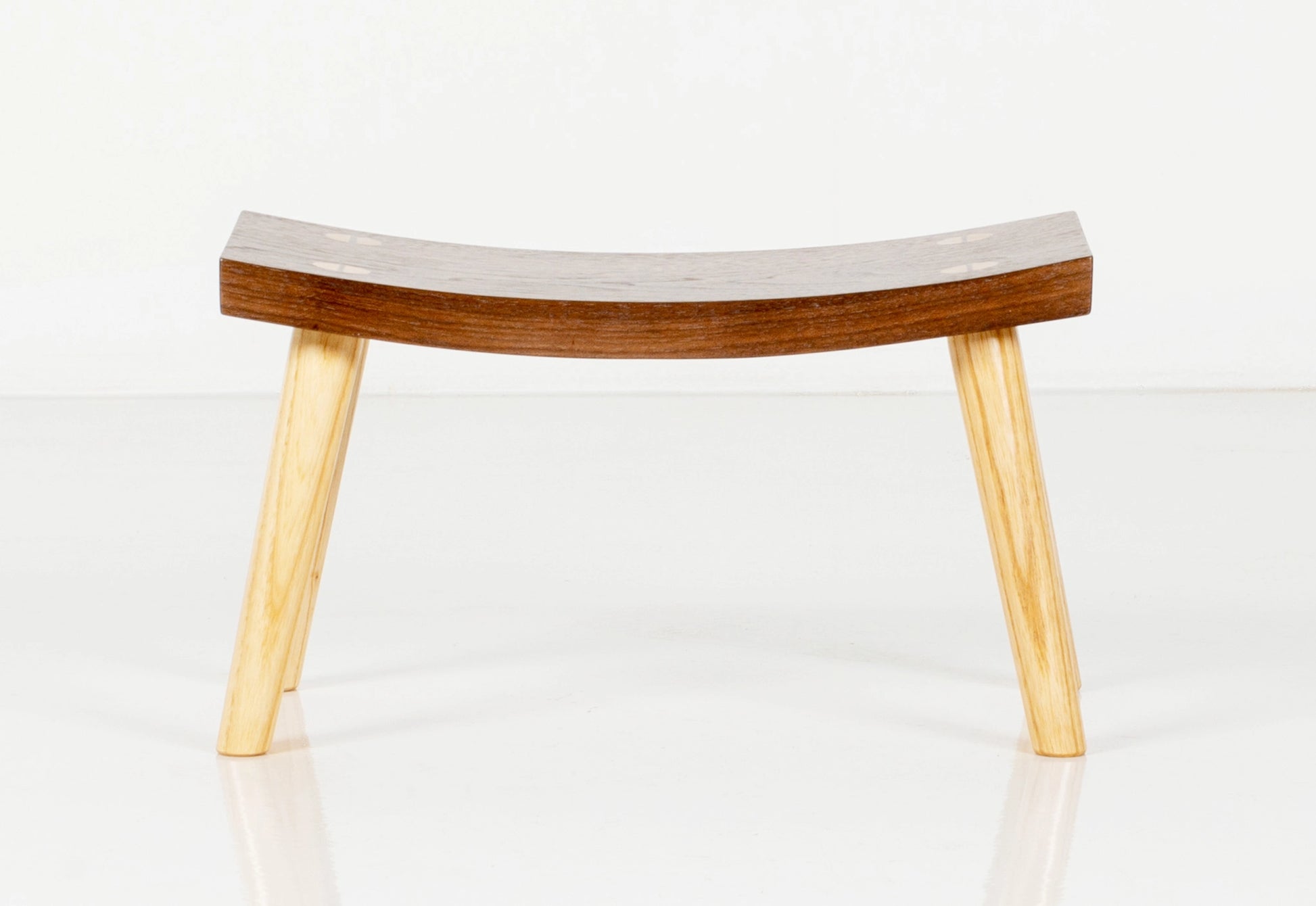 Wooden stool with curved seat on a white background