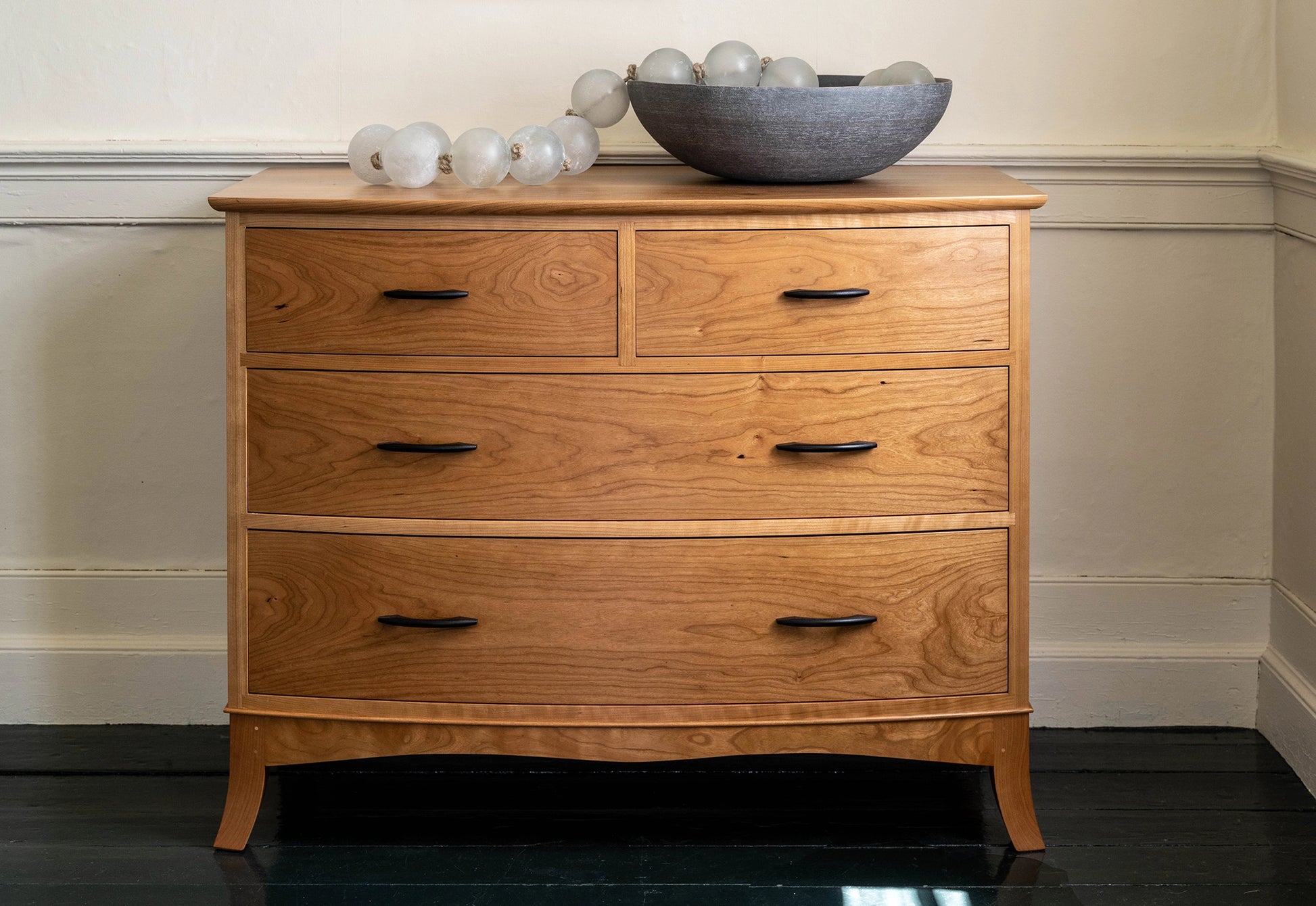 Wooden dresser with four drawers against a white wall