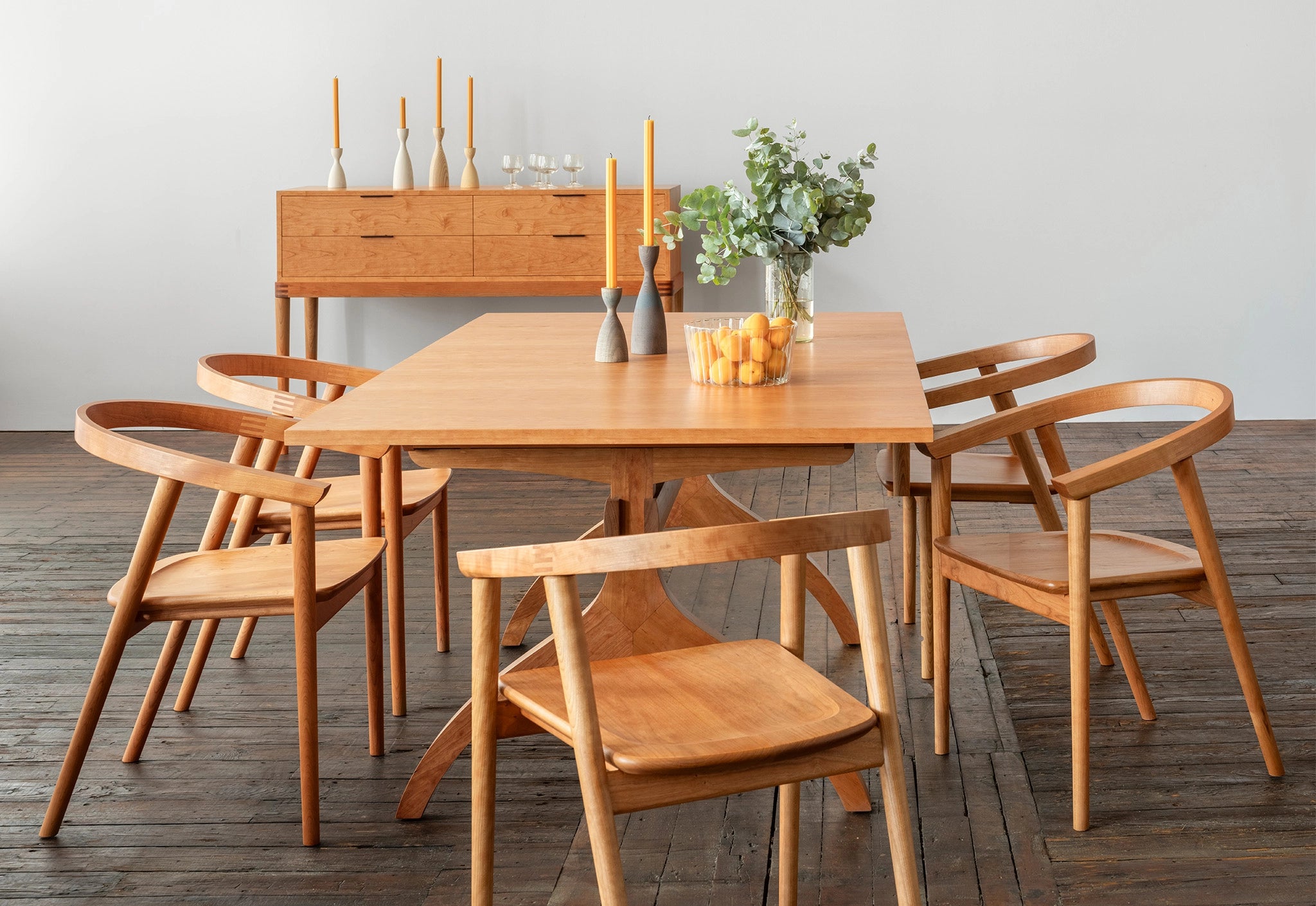 Wooden dining set with table and chairs in a room with a light gray wall.