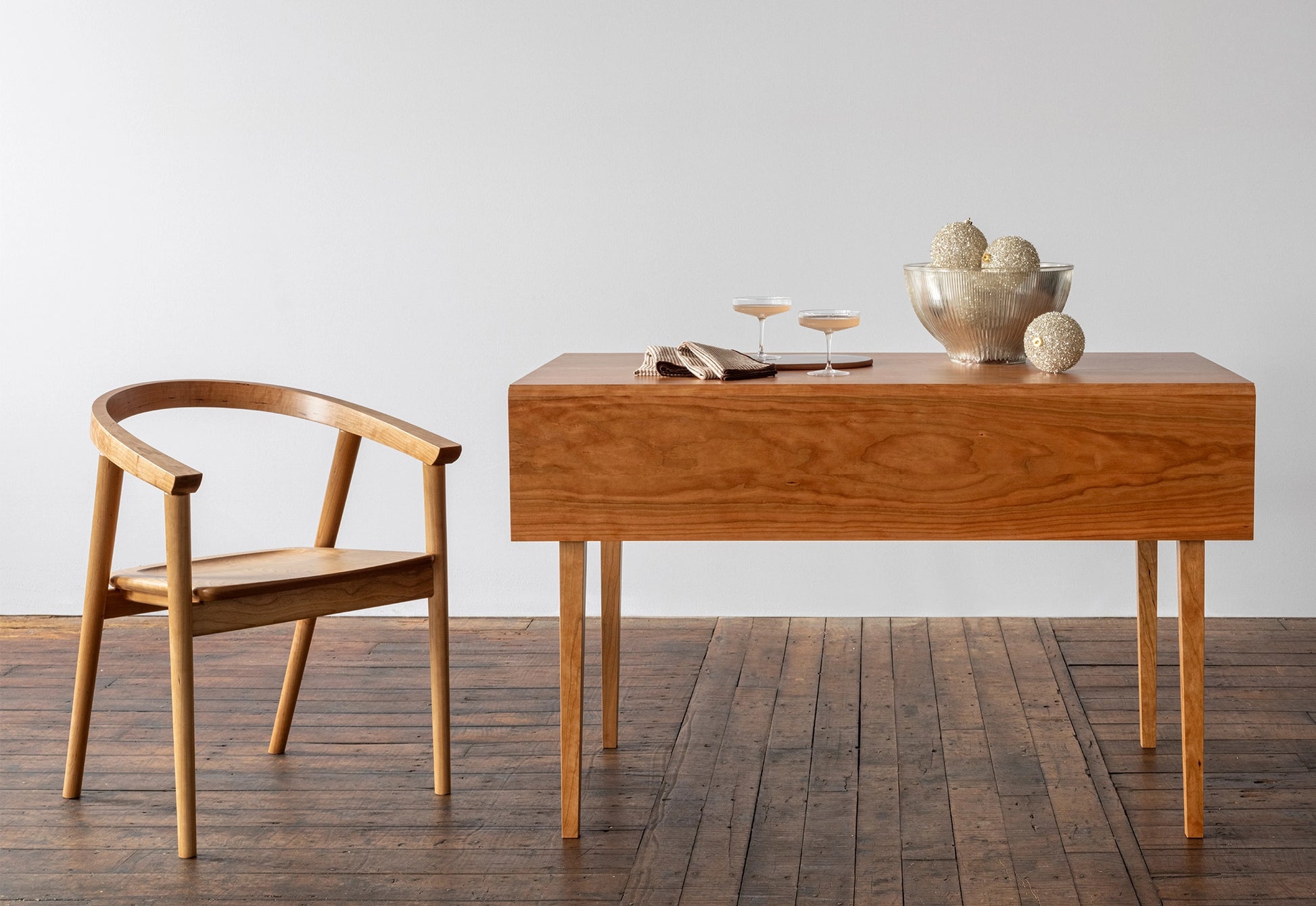 Wooden desk and chair on a wooden floor with a plain white wall background
