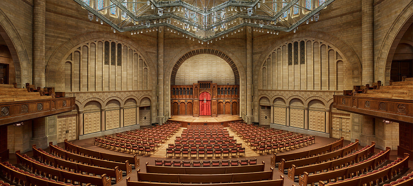 Large auditorium with rows of wooden seats and a central stage.