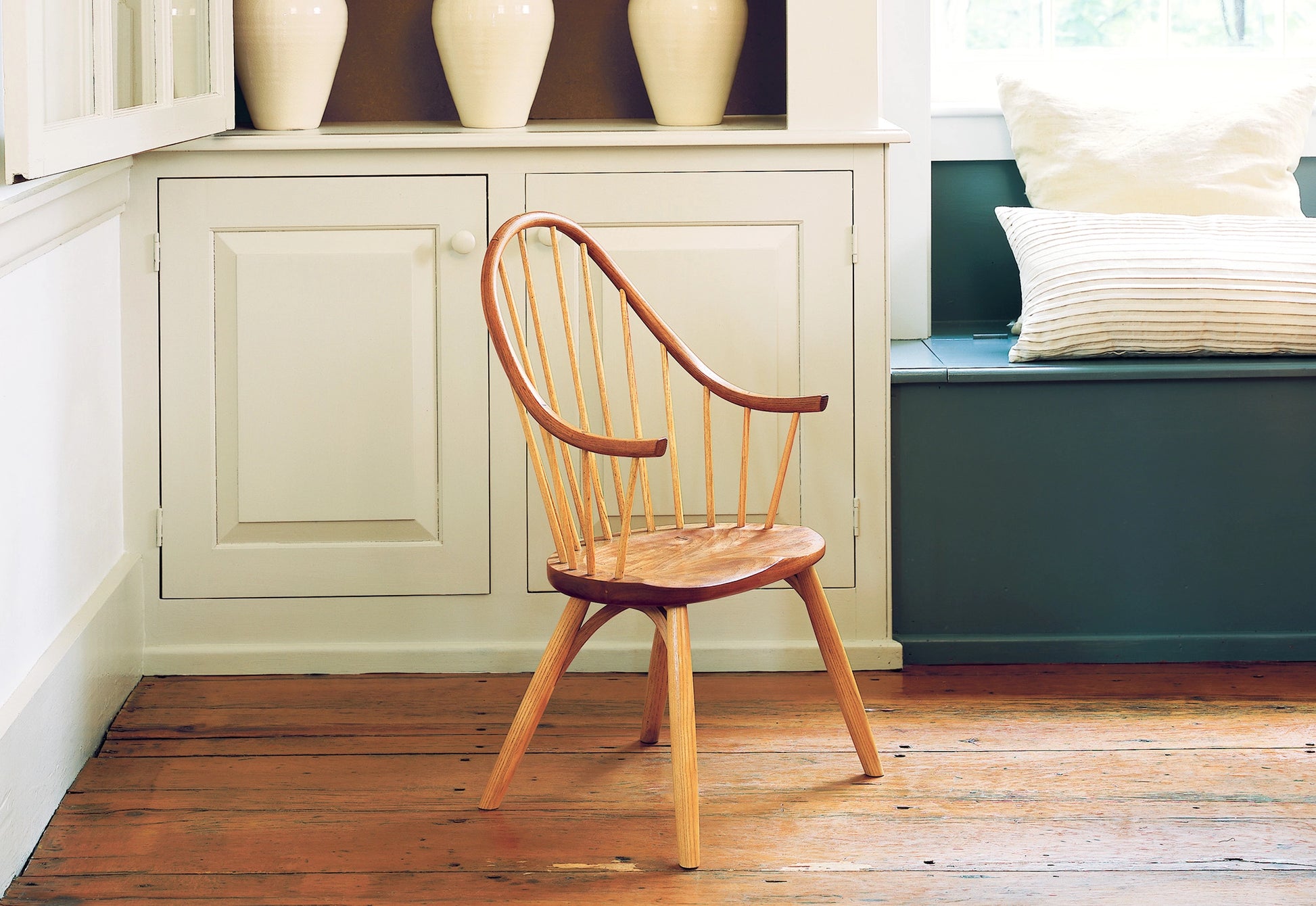 Child's wooden chair in a room with green bench and white cabinets