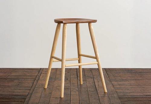 Wooden bar stool on a wooden floor with a white wall background