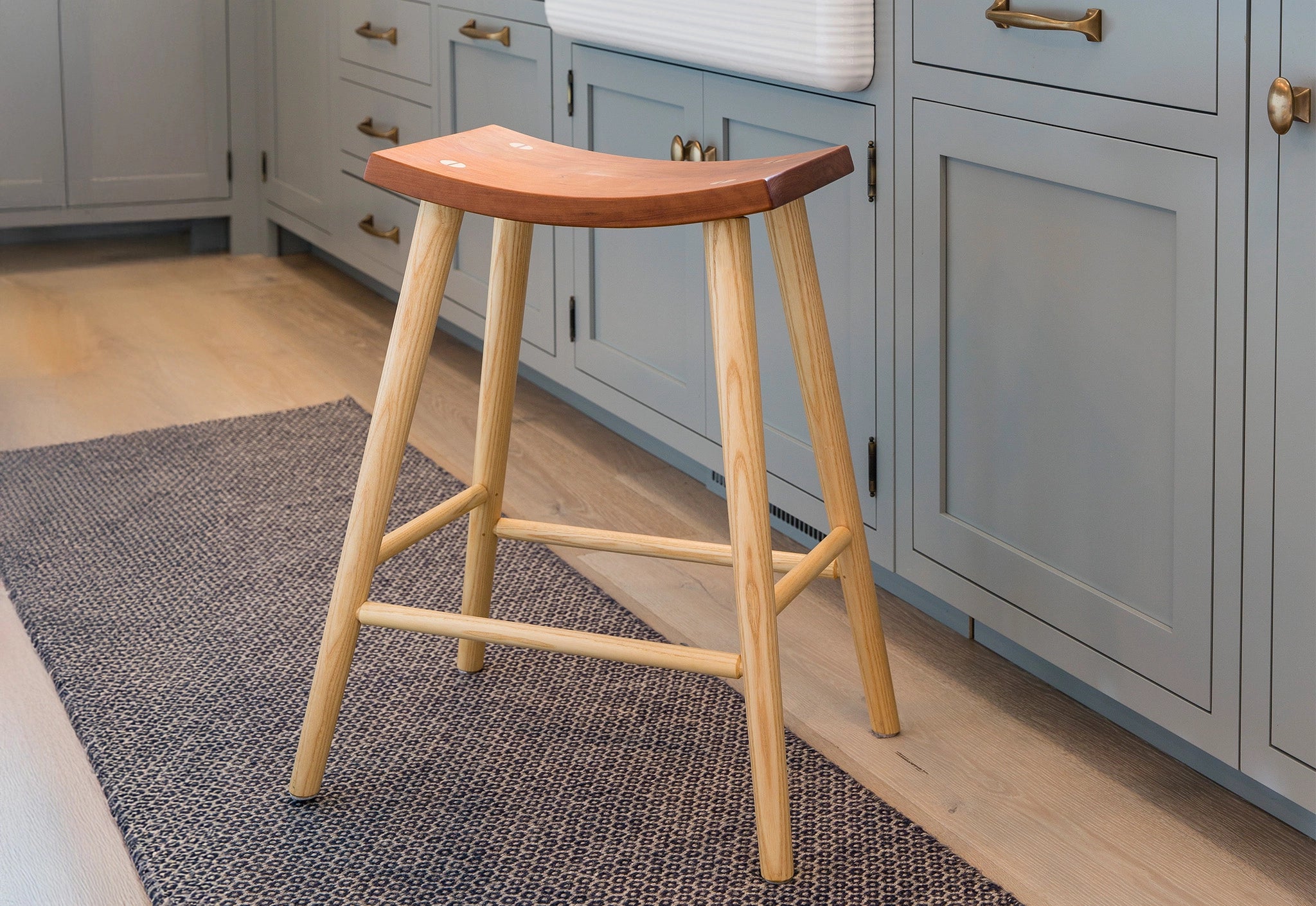 Wooden bar stool in a kitchen setting with light gray cabinets.
