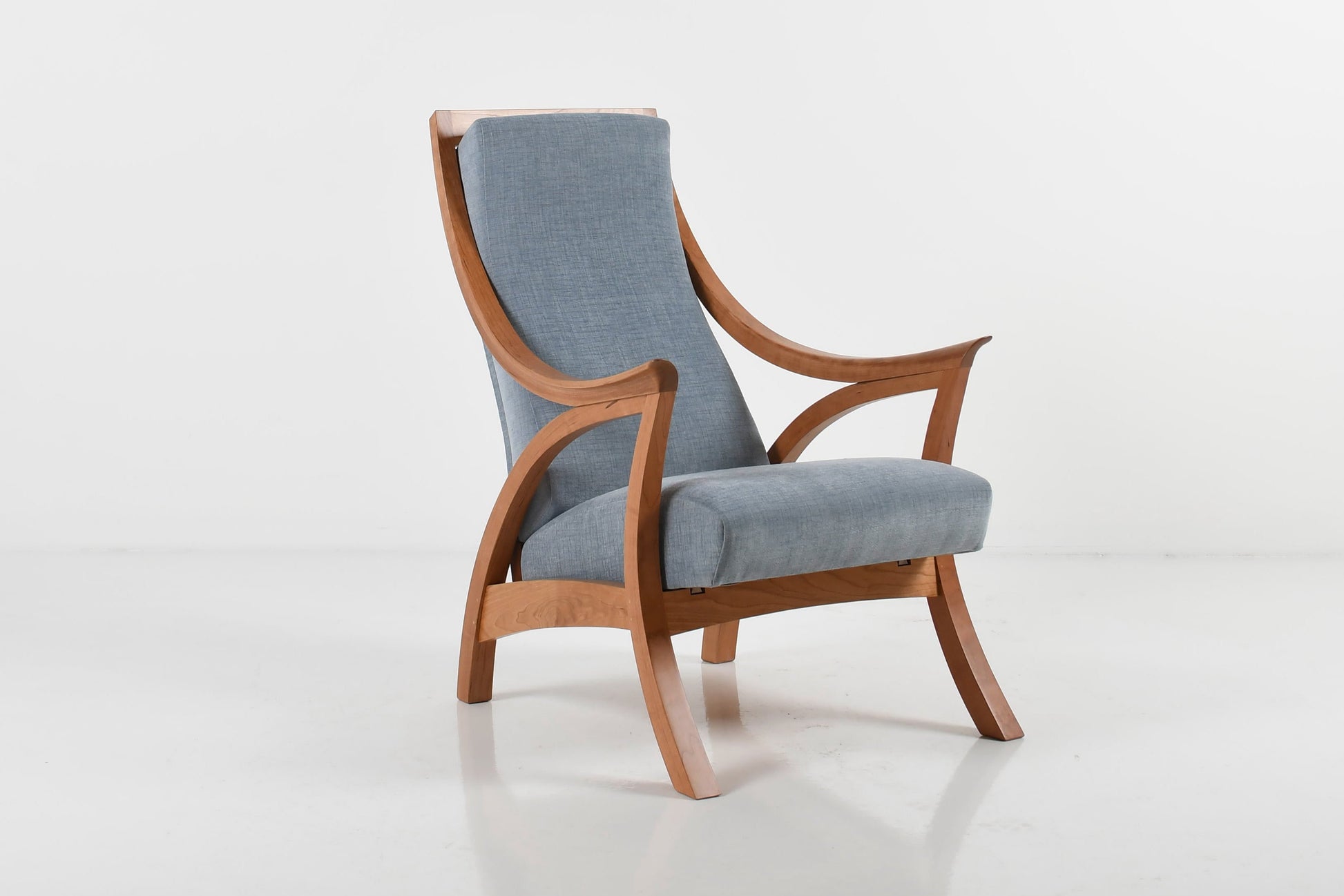 Modern chair with wooden frame and light blue cushion on a white background