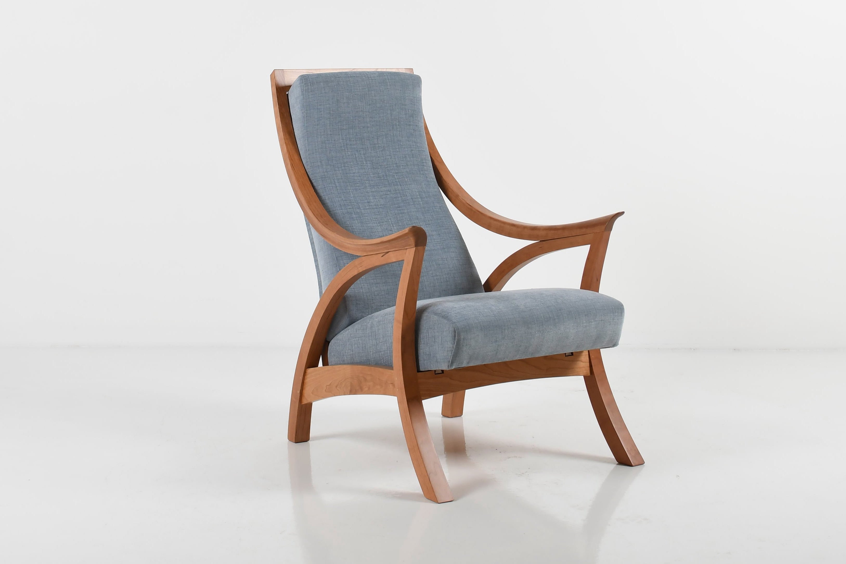 Modern chair with wooden frame and light blue cushion on a white background
