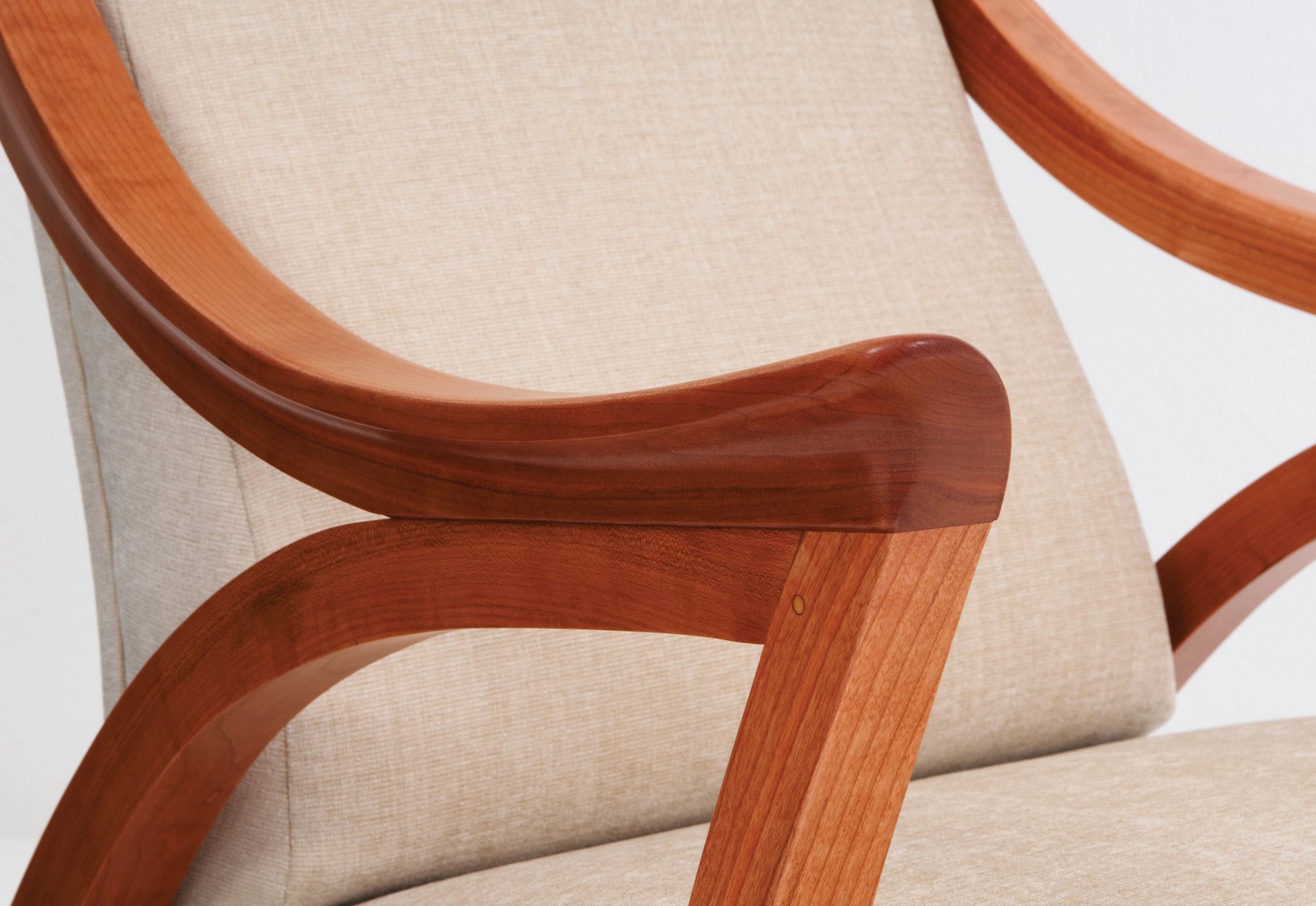 Close-up of a chair with wooden armrests and beige cushioned seat.