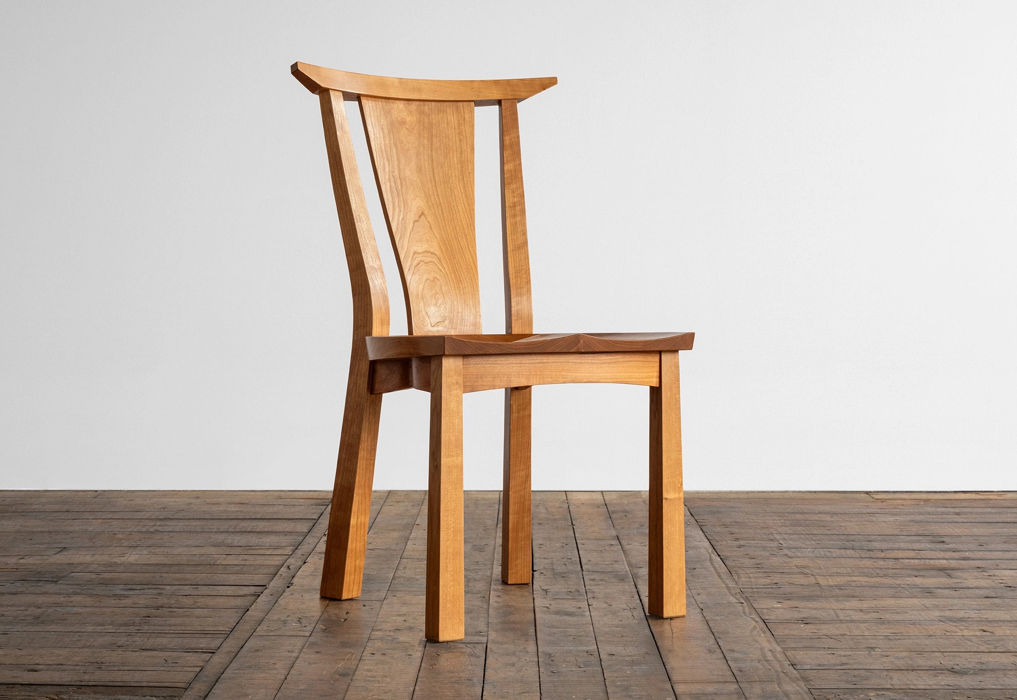 Wooden chair on a wooden floor with a white wall background