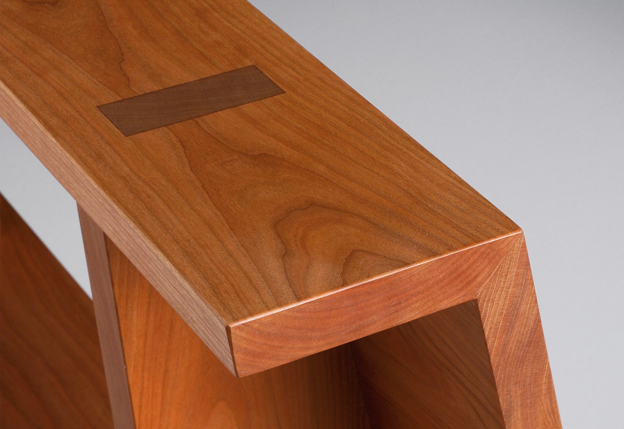 Wooden desk with a rectangular cutout on a plain background