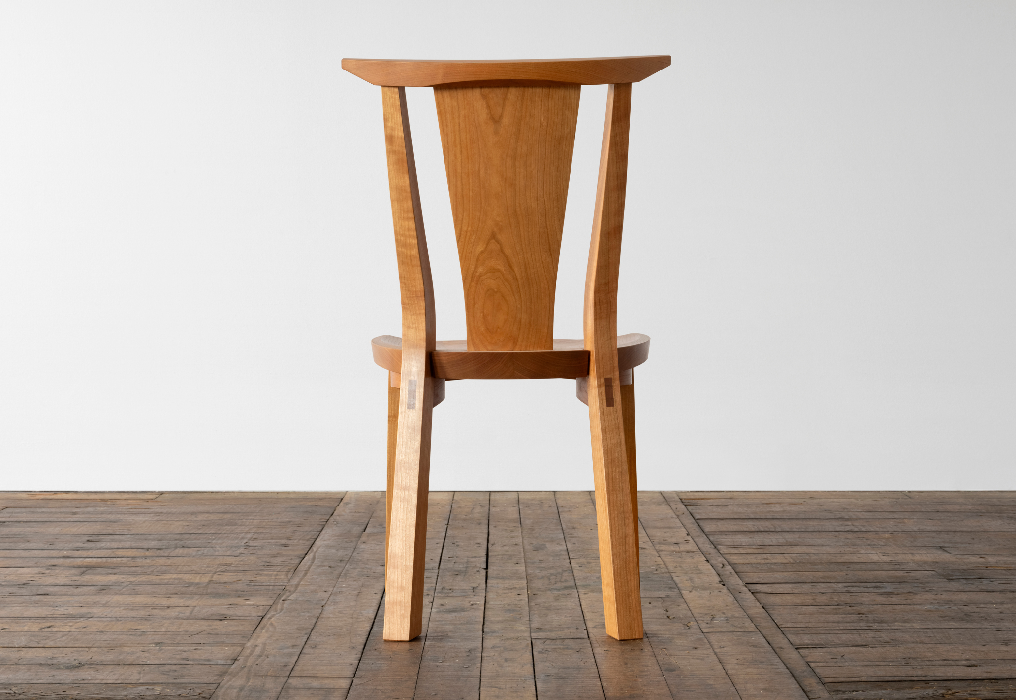 Wooden chair on a wooden floor with a white wall background