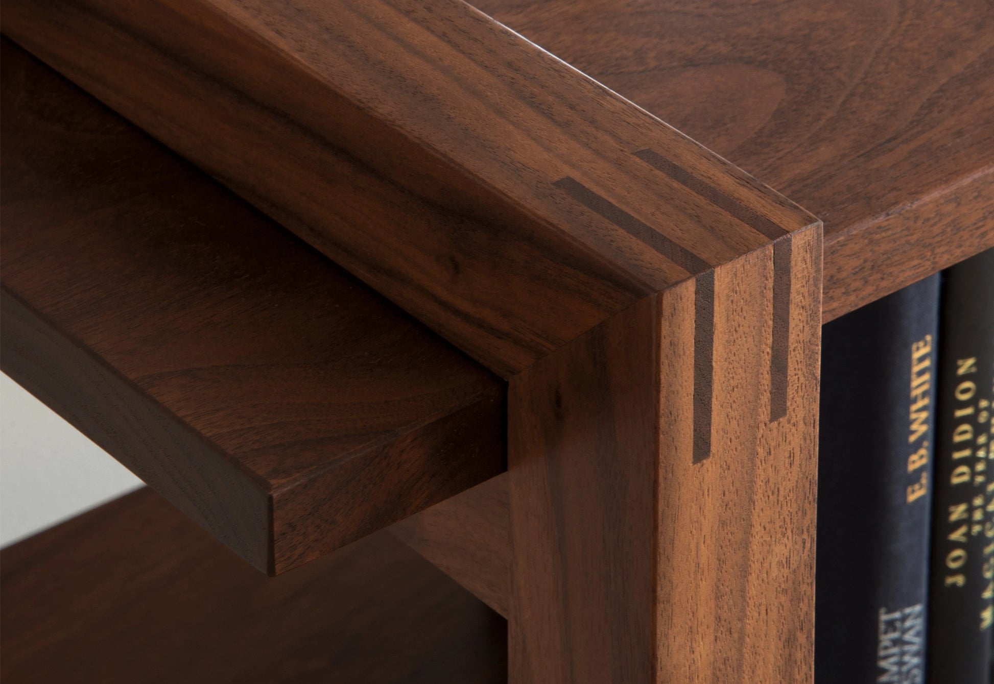 Close-up of a wooden bookshelf corner with books partially visible.