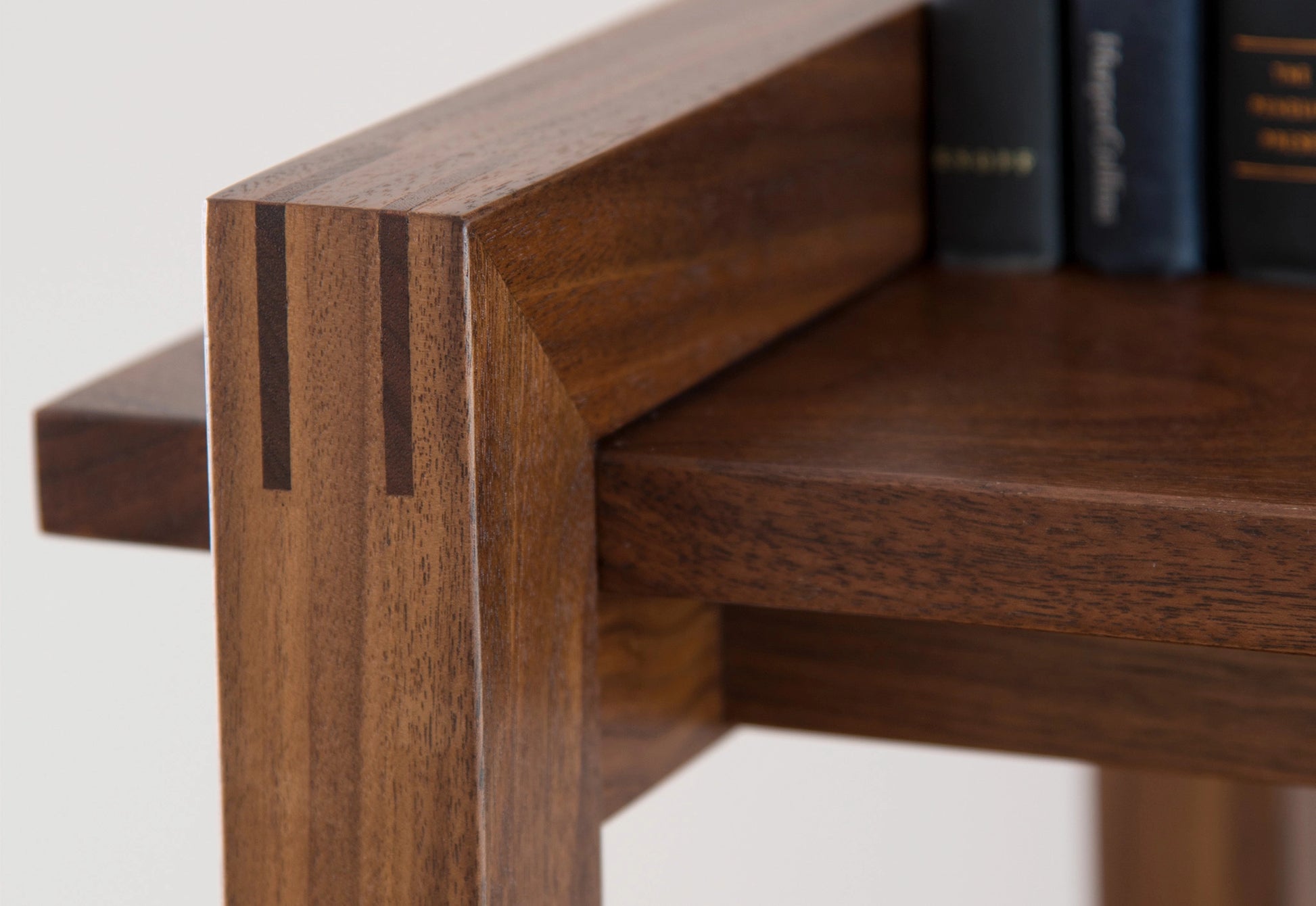 Close-up of a wooden shelf with books in the background