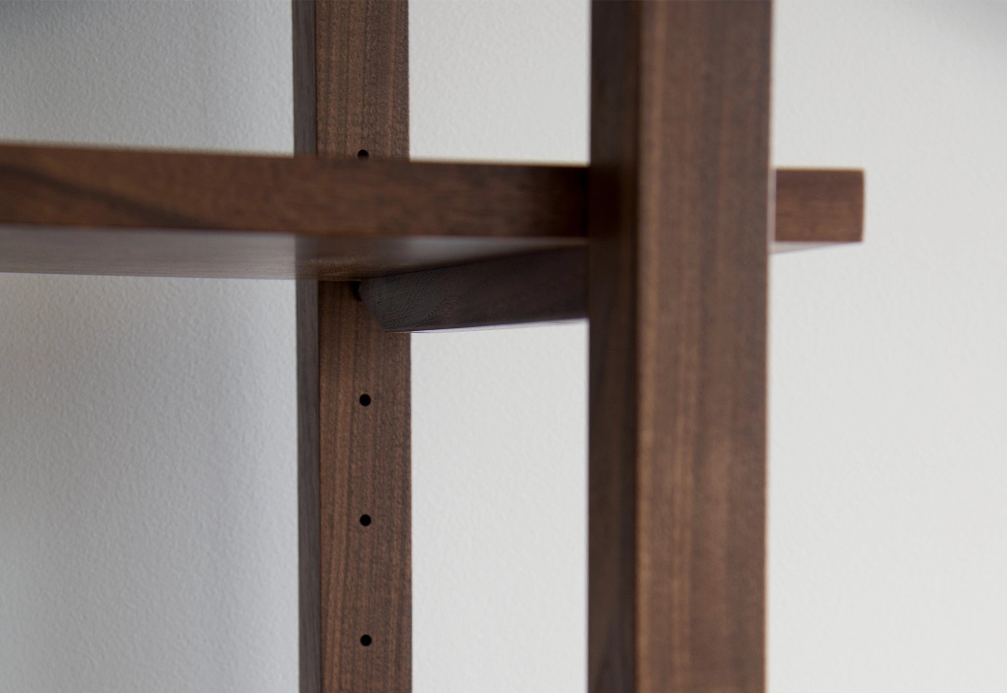 Wooden bookshelf detail on a white wall