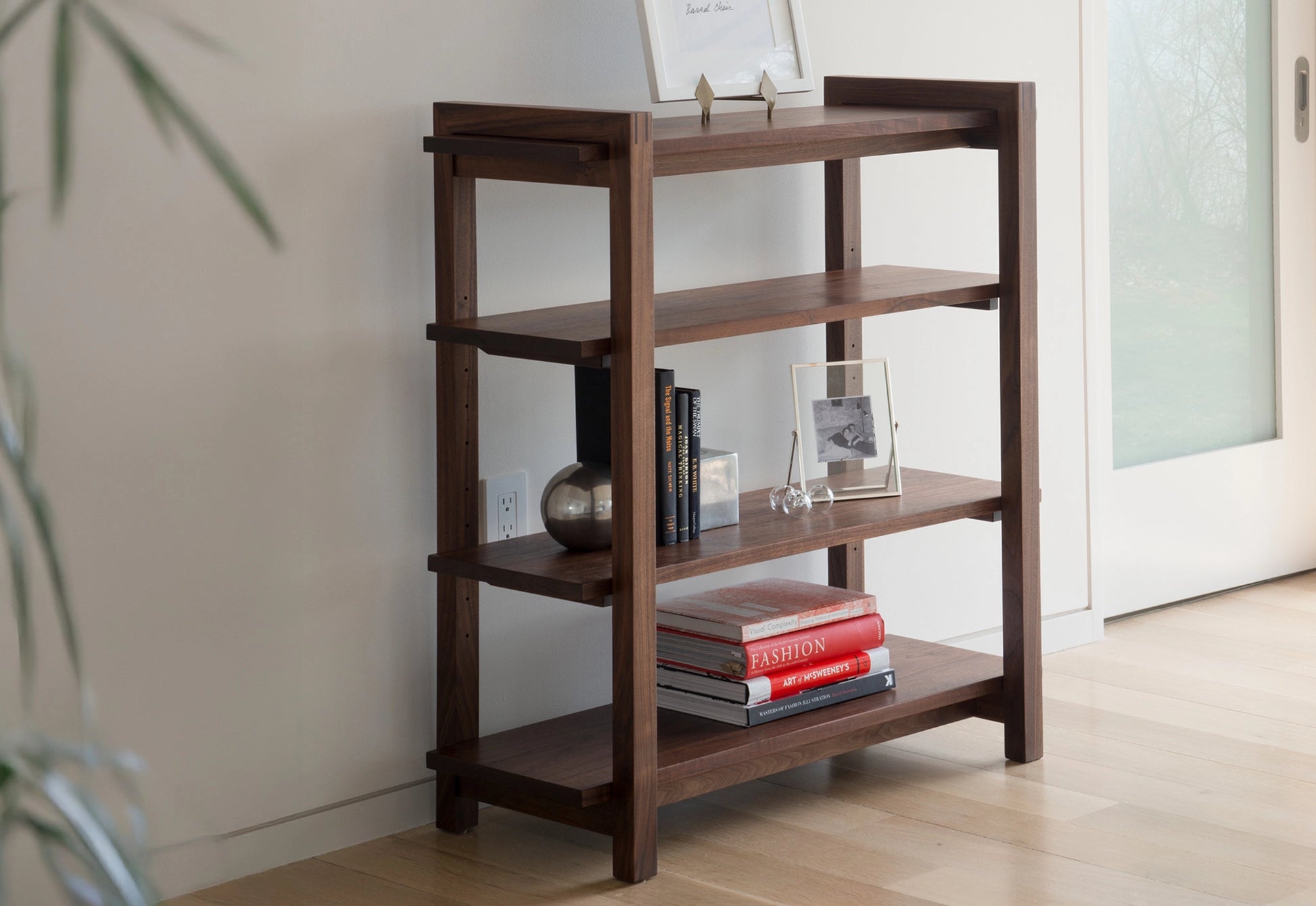 Wooden bookshelf with books and decor items against a neutral wall.