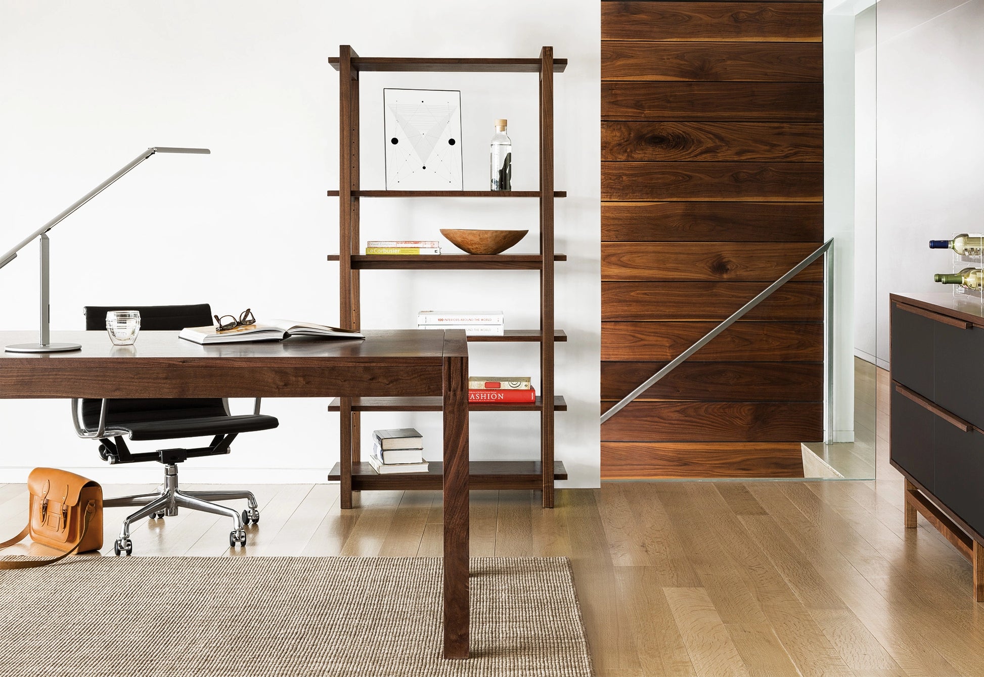 Modern office setup with wooden desk, chair, and bookshelf.