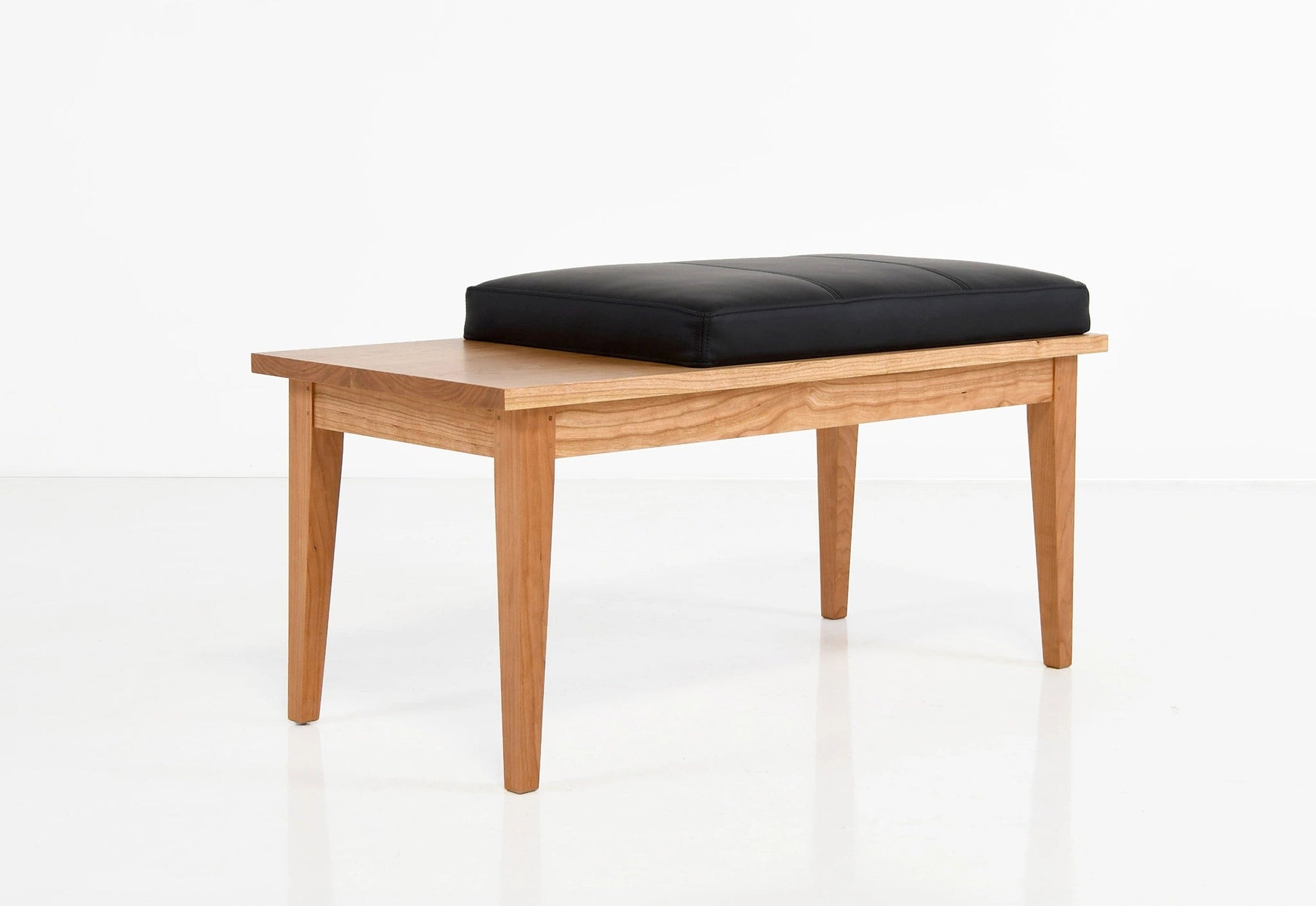 Wooden bench with a black cushion on a white background