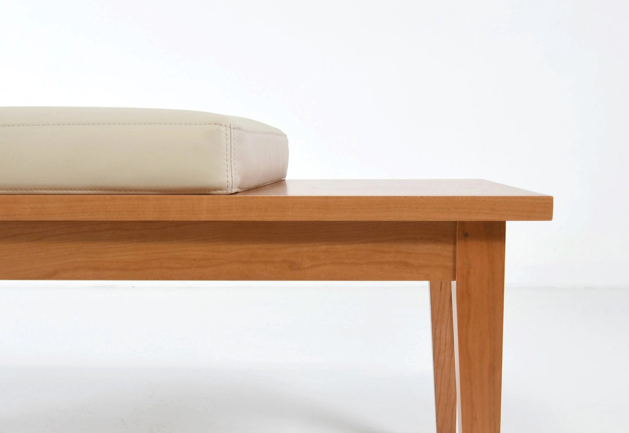 Wooden bench with a beige cushion on a white background