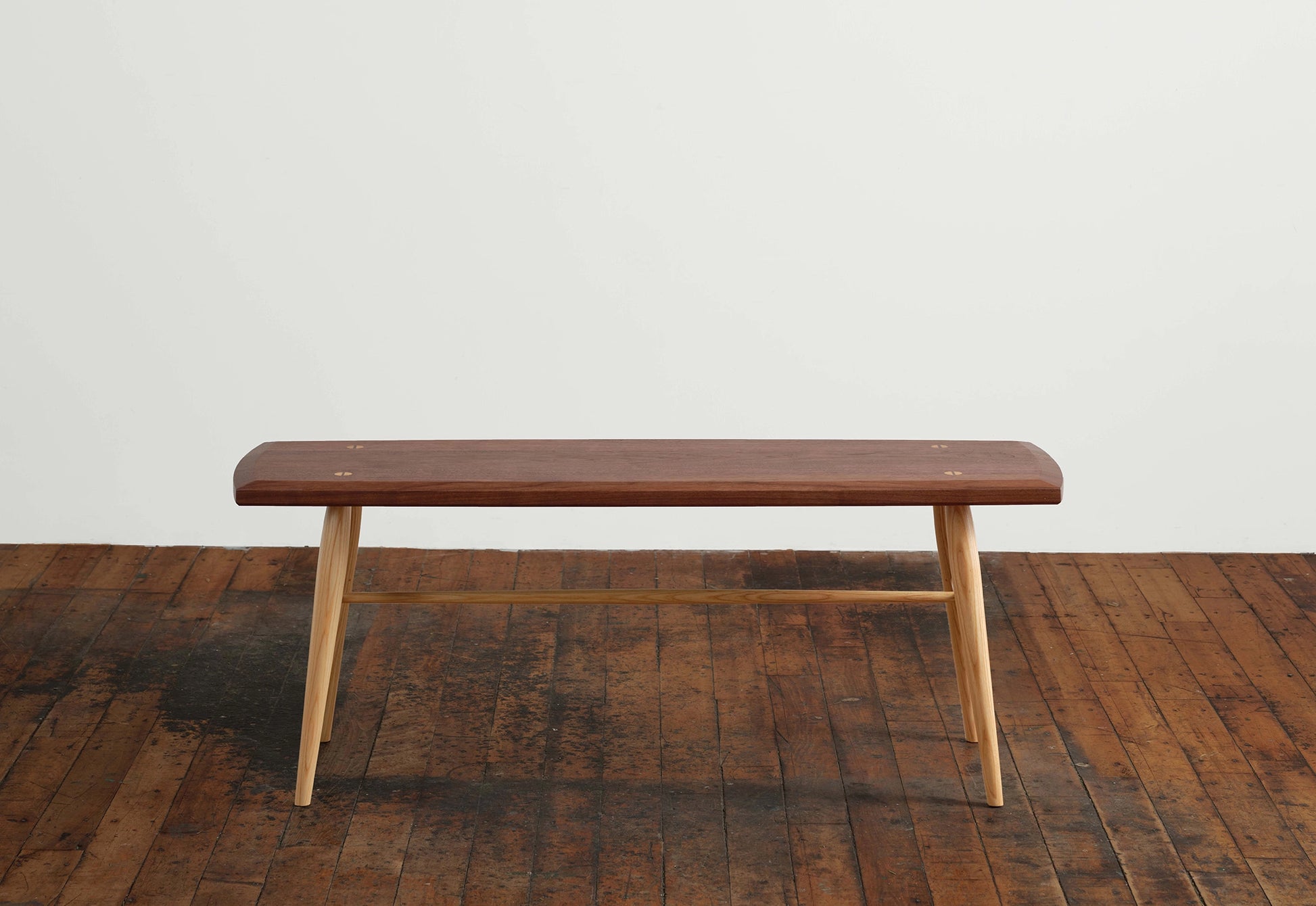 Wooden bench on a wooden floor with a white wall background