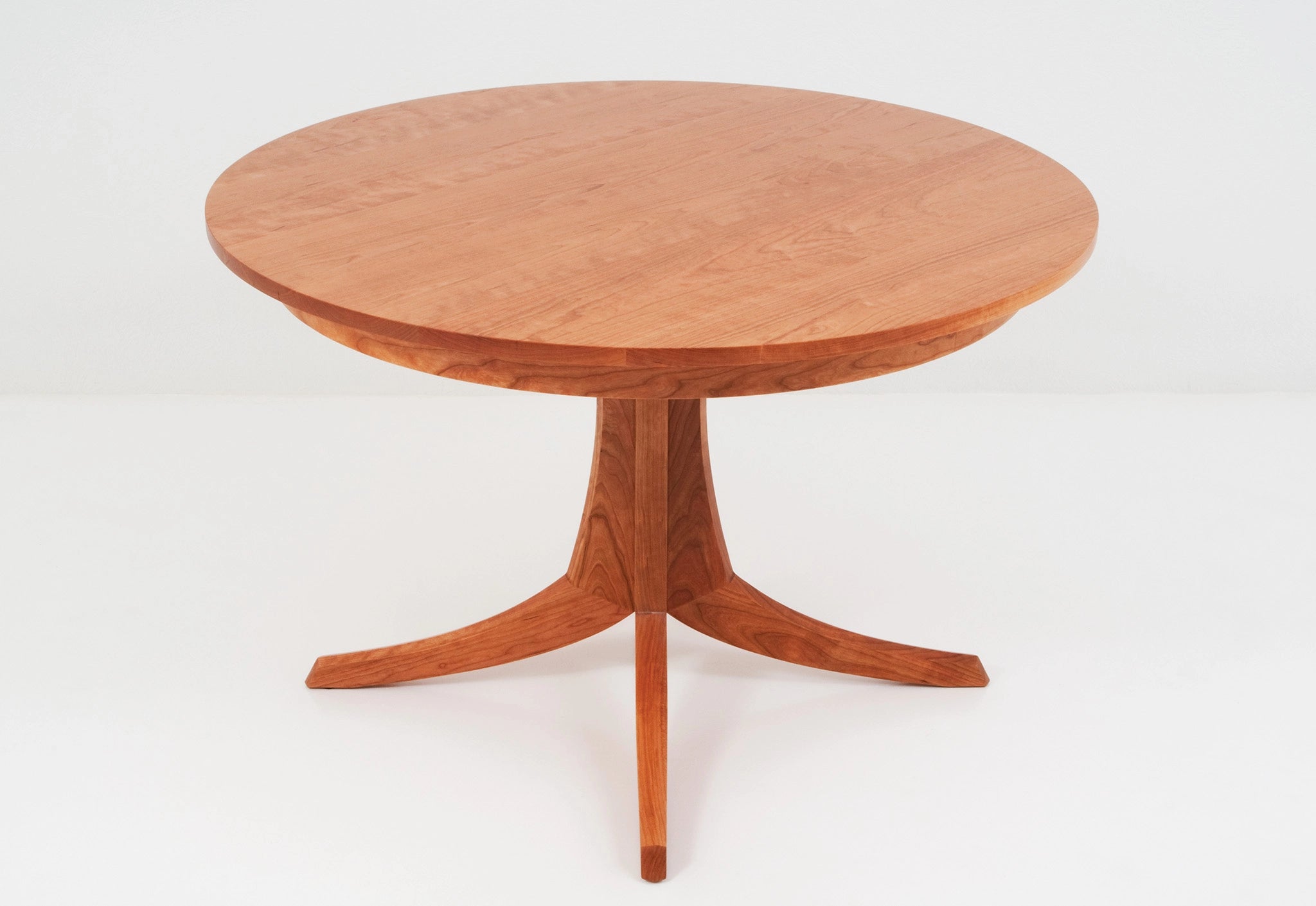 Wooden round table with a pedestal base on a white background