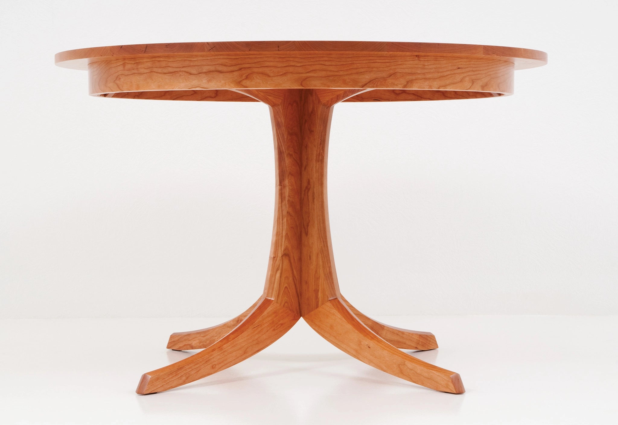 Wooden round table with a pedestal base on a white background
