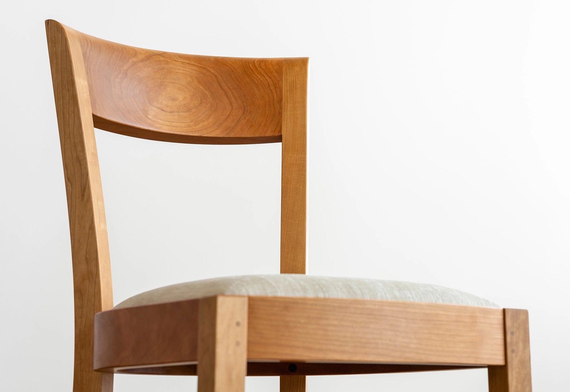 Wooden chair with a white cushion on a light gray background