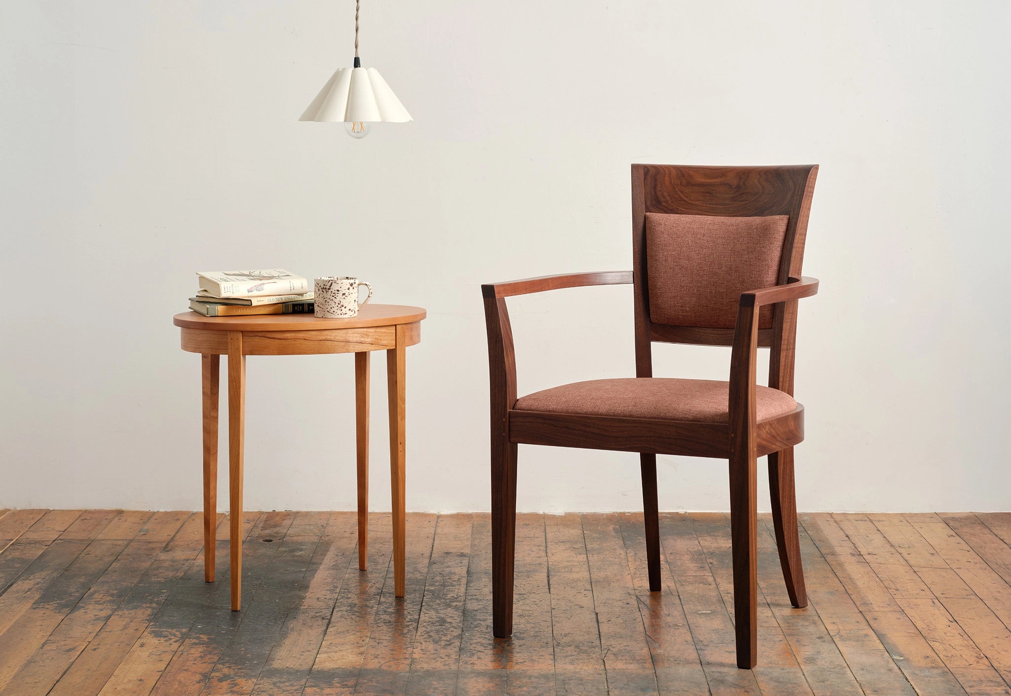 Wooden chair and side table against a white wall on a wooden floor