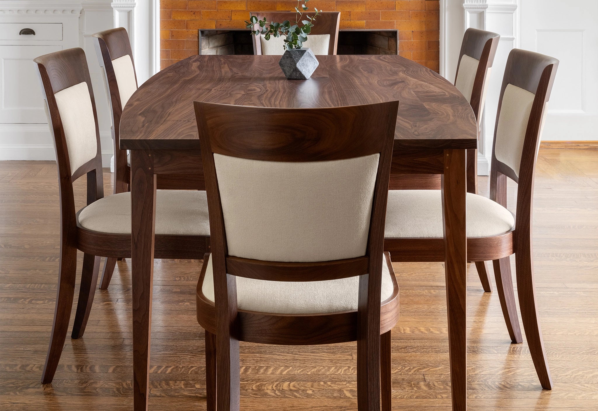 Dining room with wooden table and chairs on a wooden floor.